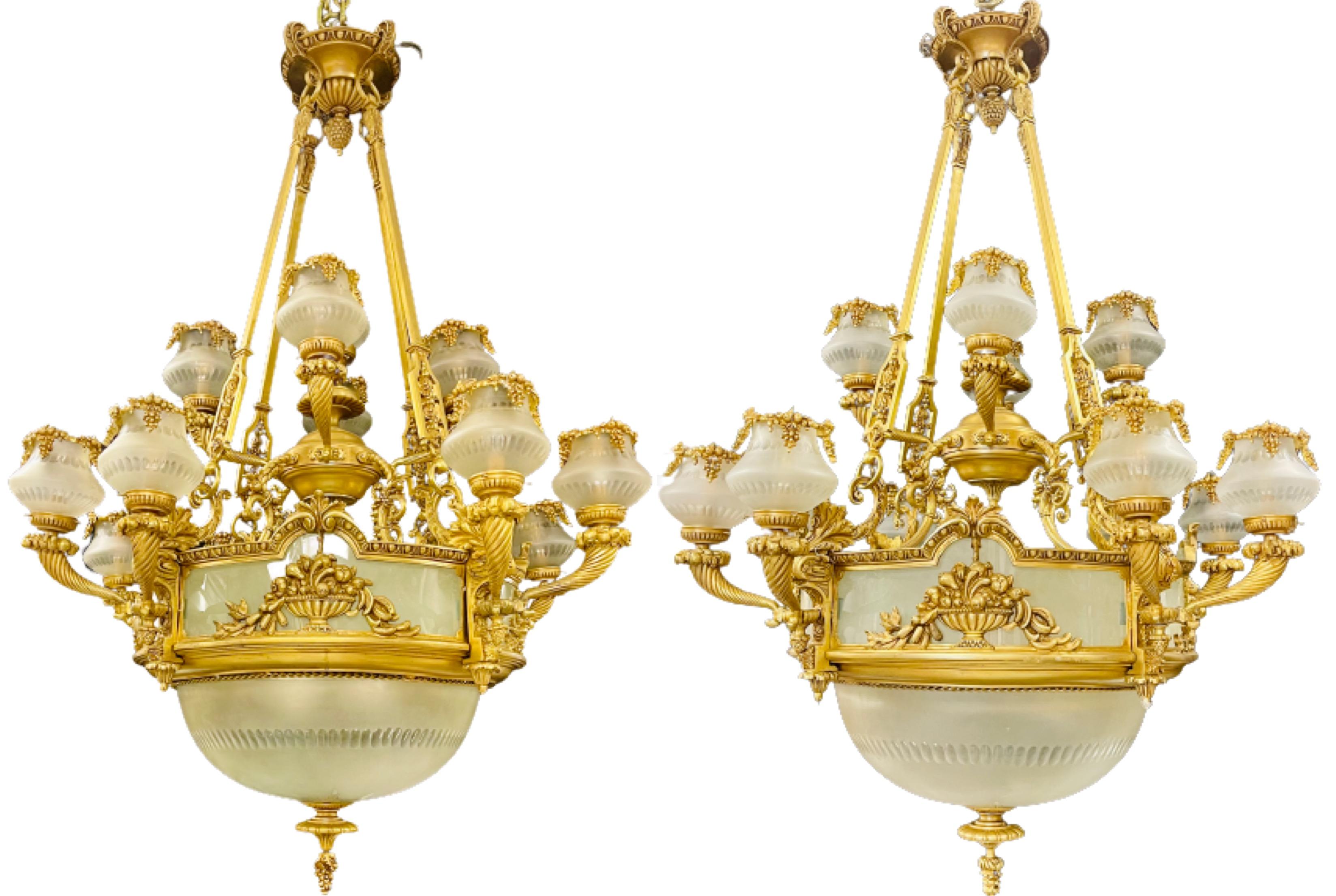 Paire de lustres en bronze de style Louis XVI. Une grande et impressionnante paire de lustres palatiaux en bronze doré ayant 13 bras lumineux avec quatre ampoules à l'intérieur de la grande coupe en verre dépoli. Ce lustre finement moulé a une