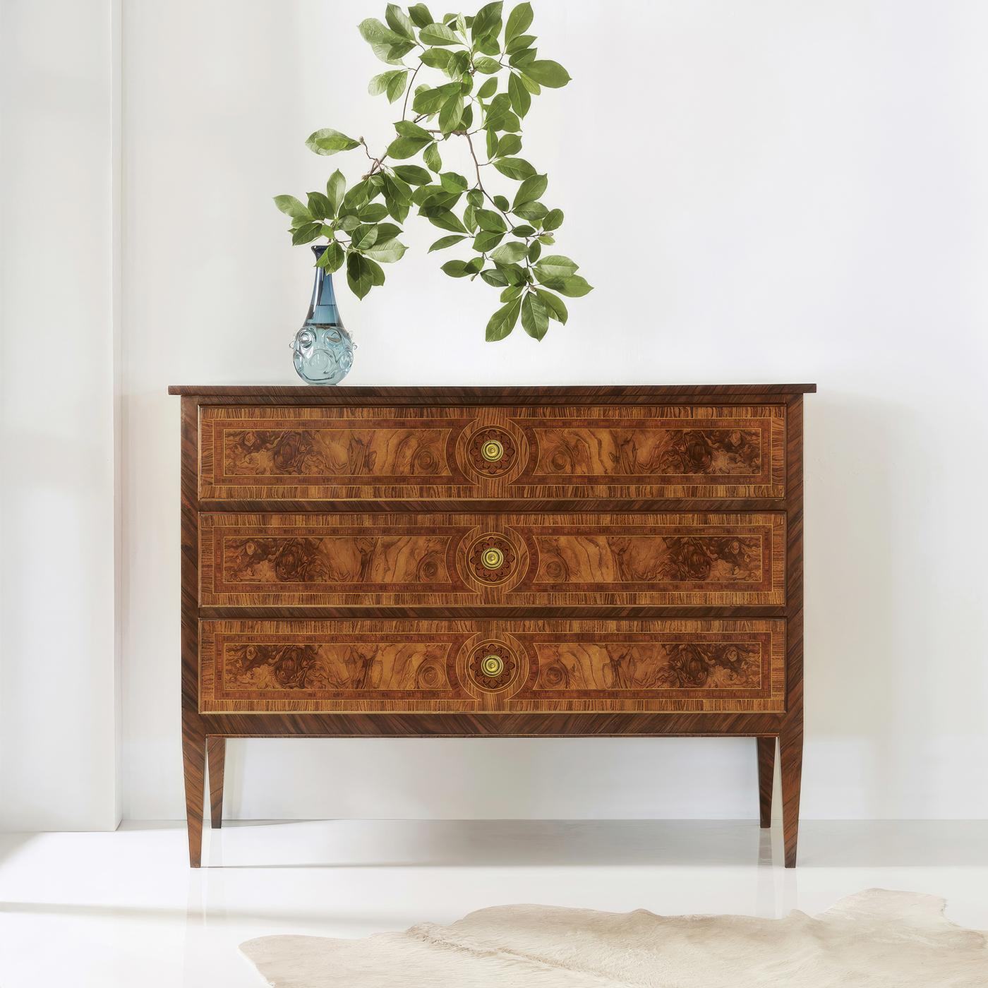 Ce coffre incarne l'élégance raffinée du design français du XVIIIe siècle grâce à l'utilisation magistrale de placages de loupe assortis et d'incrustations délicates. Chaque façade de tiroir présente des motifs de ronce symétriquement disposés,