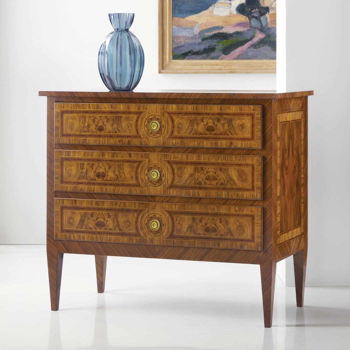 Nightstand embodies the refined elegance of 18th-century French design through its masterful use of book-matched burl veneers and delicate inlays. Each drawer front showcases symmetrically arranged burl patterns framed by precise stringing and cross