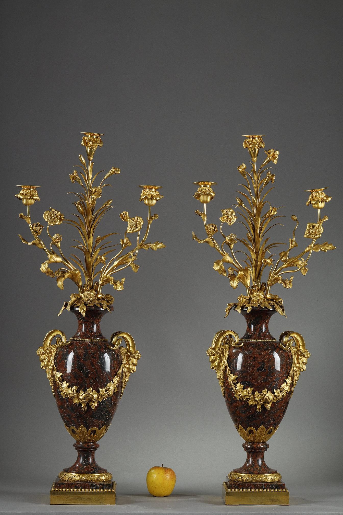 Coppia molto grande e bella di candelabri in stile Luigi XVI in marmo rosso griotte con montature in bronzo cesellato e dorato, con tre bracci di luce in rami fioriti di garofani e rose, il corpo circondato da un perlé affiancato da due maschere di