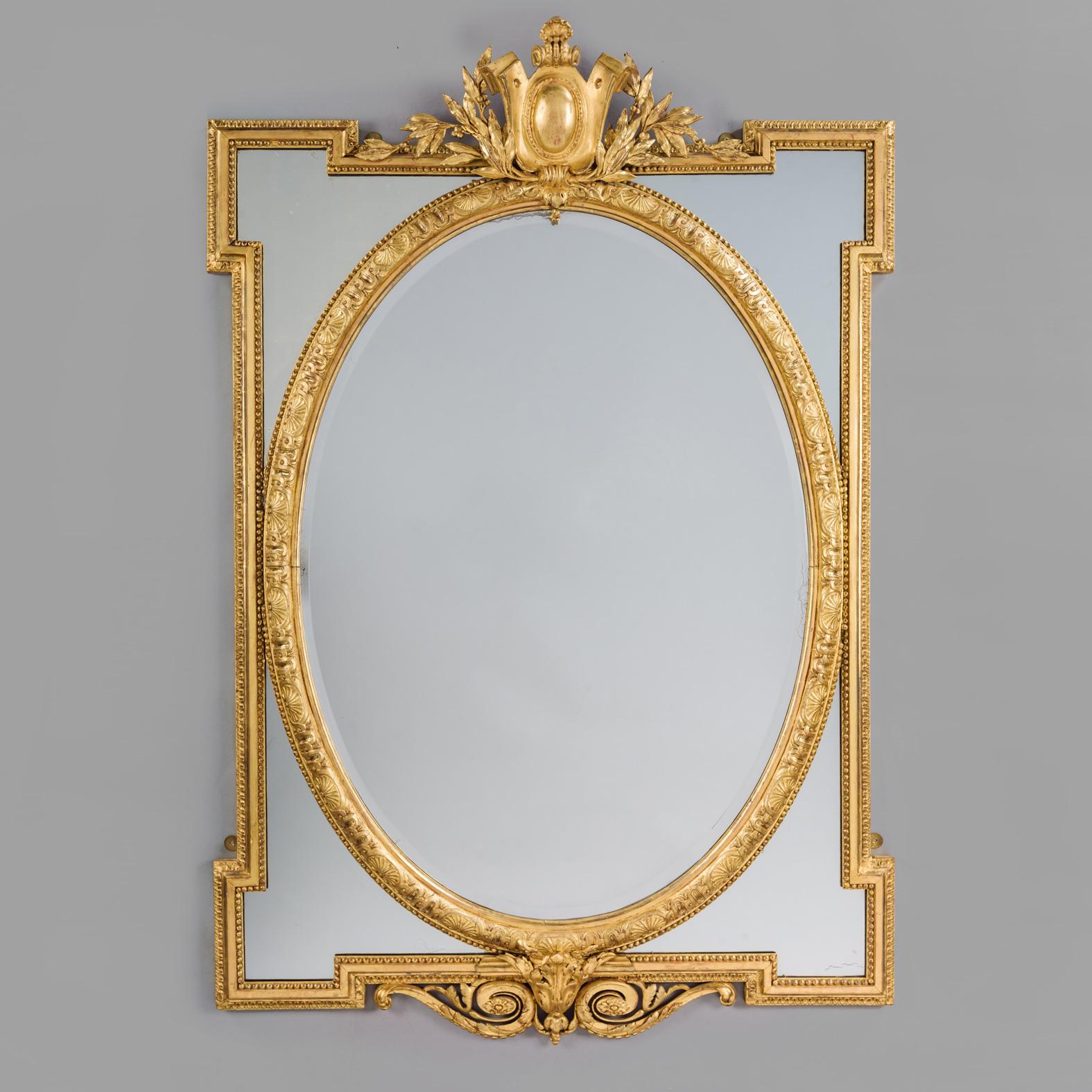 Paire de miroirs à encadrement marginal en bois doré de style Louis XVI. 

Cette paire de miroirs en bois doré et en géso sculpté présente une plaque ovale biseautée encadrée de quatre écoinçons en miroir dans des bordures moulées de perles et de