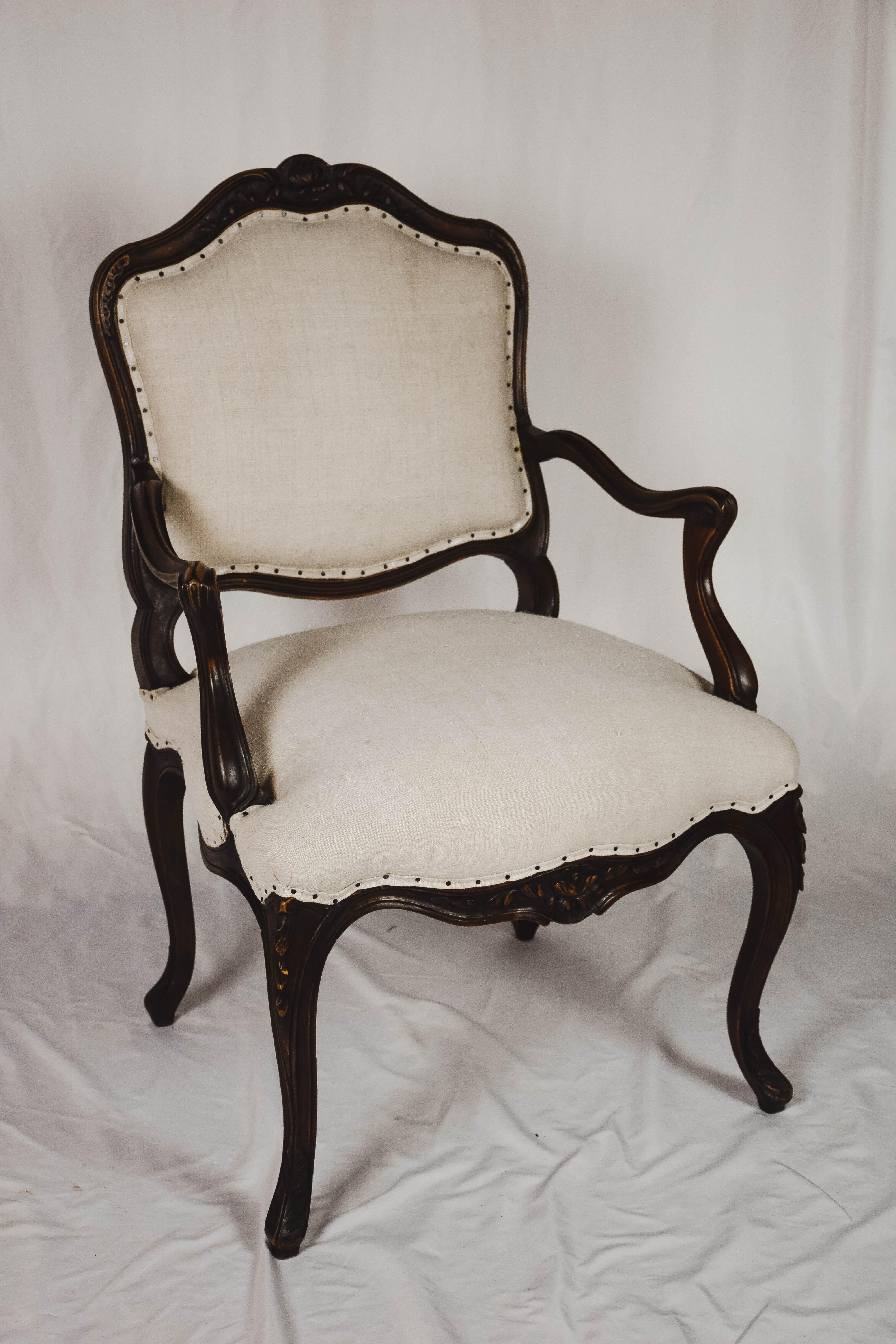 Found in Provence, a pair of Louis XVI walnut fauteuil armchairs with nicely carved details. The chairs, with a wood support on the back and padded arms are sturdy and have been newly upholstered in a vintage linen fabric and small nail heads.
