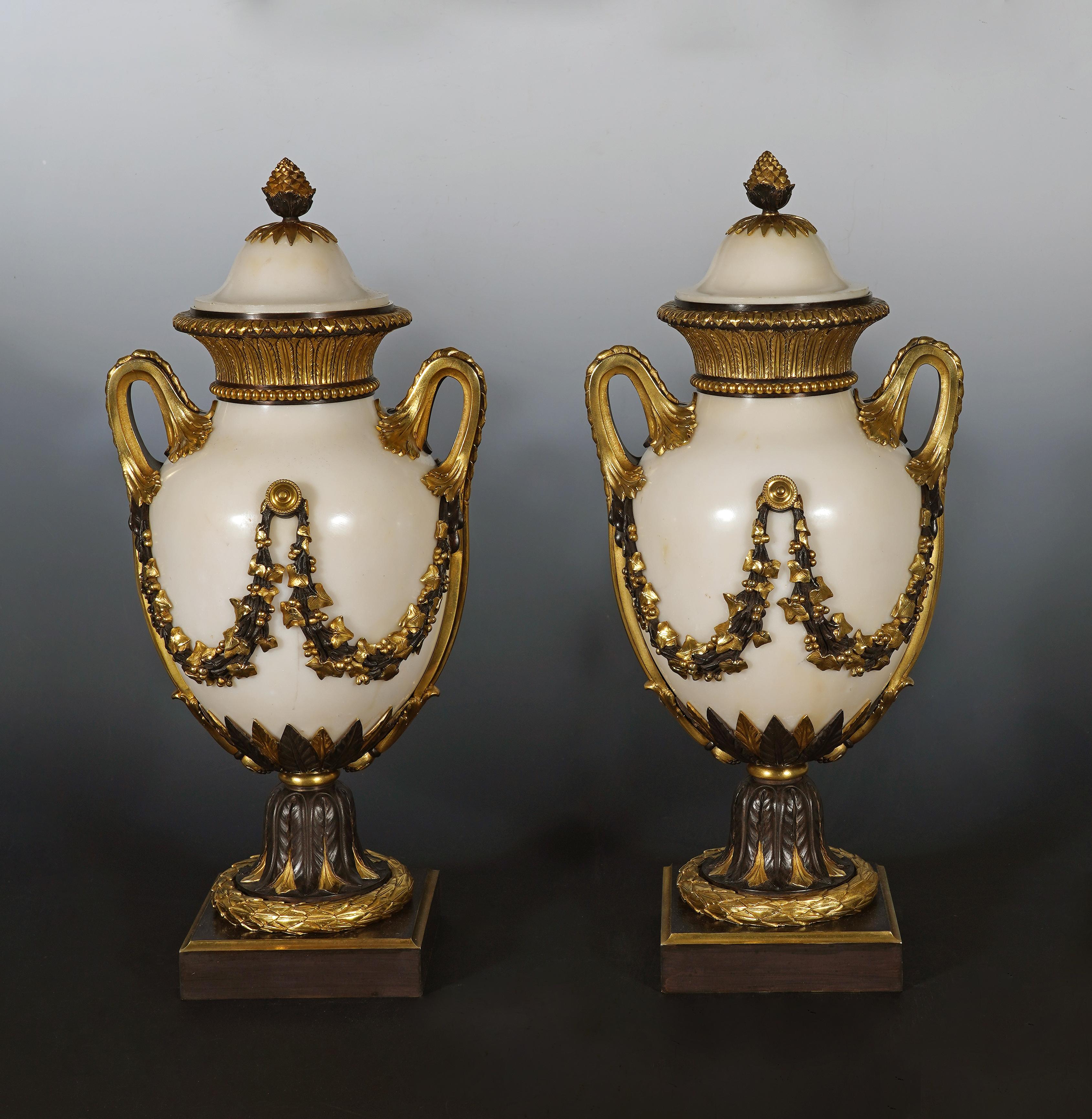 Beautiful pair of Louis XVI-inspired baluster-shaped cassolettes in white marble, enriched with an elegant bronze mount with a double patina. The lid is topped with a seed-shaped grip. 
The body is decorated with garlands of ivy attached to a