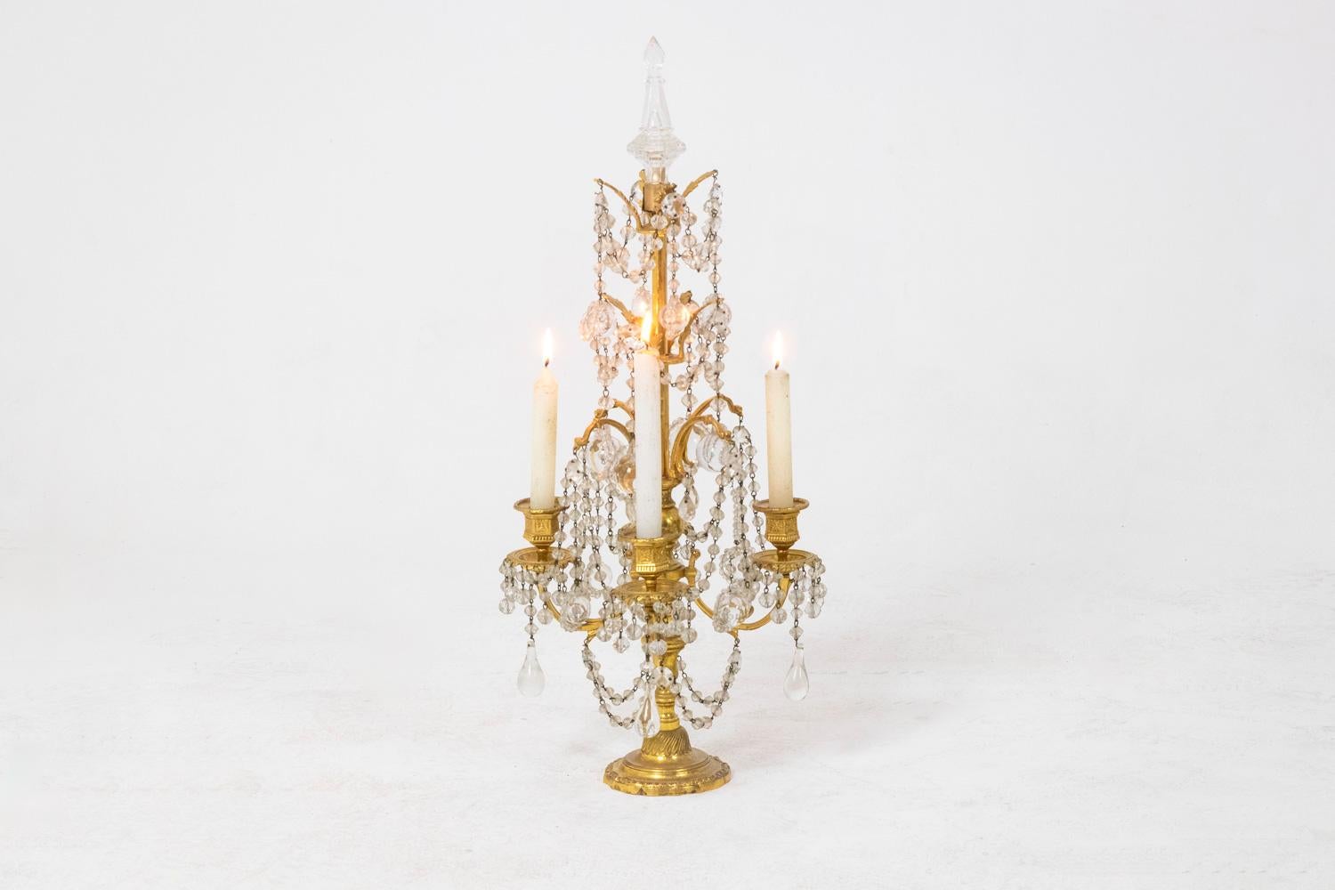 Pair of Louis XVI style candelabra in gilded bronze and crystal, with four sconces, decorated with pendants and ending in the upper part with a knife. Round shaped base.

Work realized circa 1900.