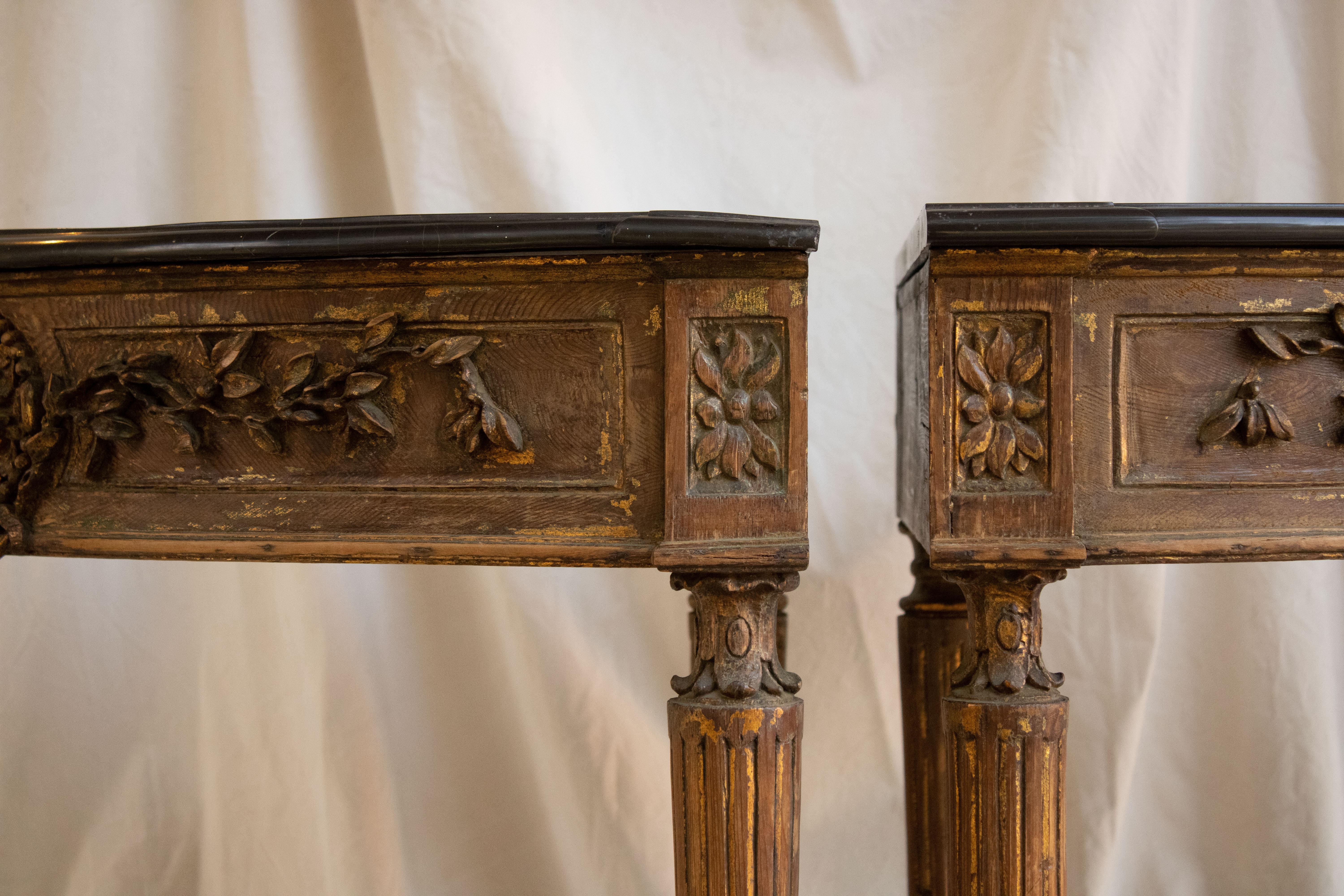 Pair of Louis XVI style corner tables.
Carved wood, with traces of ancient gold and black marble tops. 
Portugal 19th century.