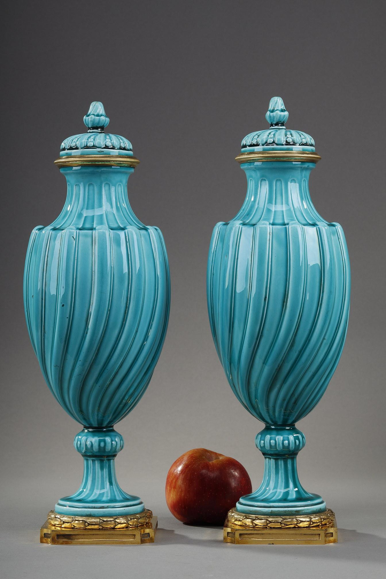 Türkisblaue Vasen aus Keramik im Louis-XVI-Stil mit gedrehtem Dekor, Paar. Sie haben eine vergoldete Bronzefassung. Er hat die Form eines Lorbeerkranzes am Fuß. Der abnehmbare Deckel ist gedreht und wird von einem Griff gekrönt. 

Es handelt sich