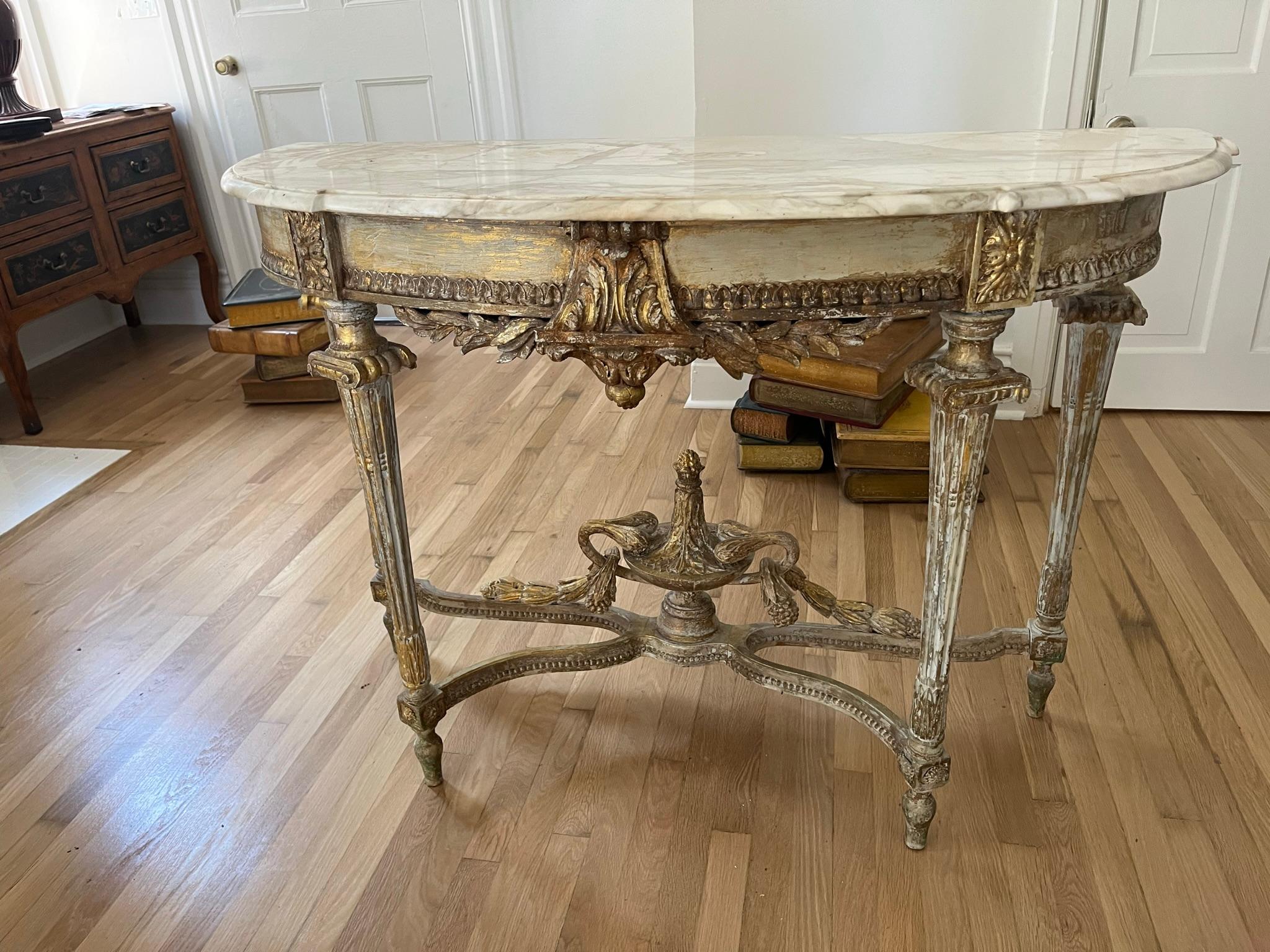 An unusual set of paint and giltwood distressed Louis Xvi style demilune shaped console tables with Gustavian type finish . Each table with a stretcher and central urn furthered  adorned with floral and foliage carved decorations in full relief .