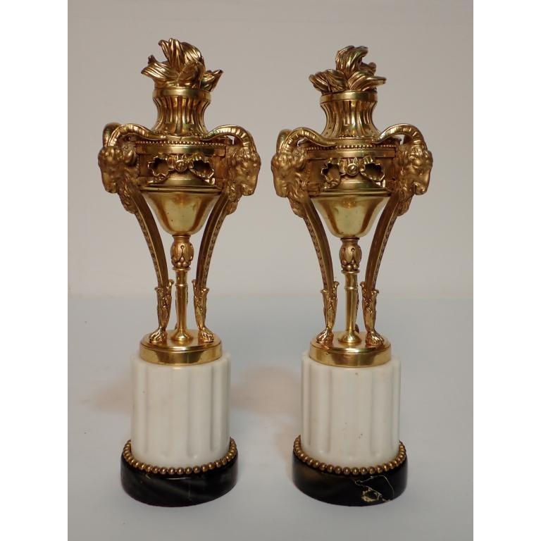French 19th Century Louis XVI gilt bronze garnitures mounted on fluted white Carrara marble and black marble bases with ram's head and flame motifs.
  