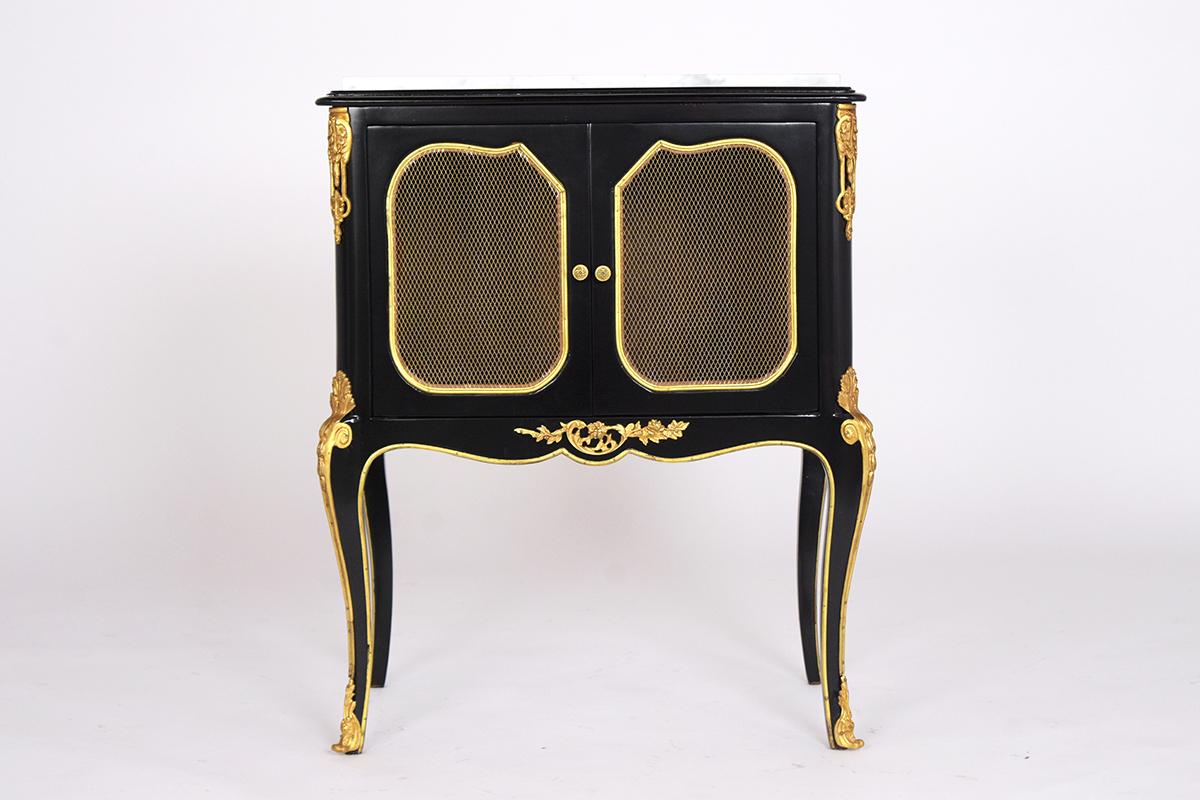This pair of 1950s French Louis XVI style nightstands have been restored and features a newly ebonized lacquered finish. They have white Carrara marble tops, underneath it has two small doors with brass wire panels, brass knobs, and brass molded
