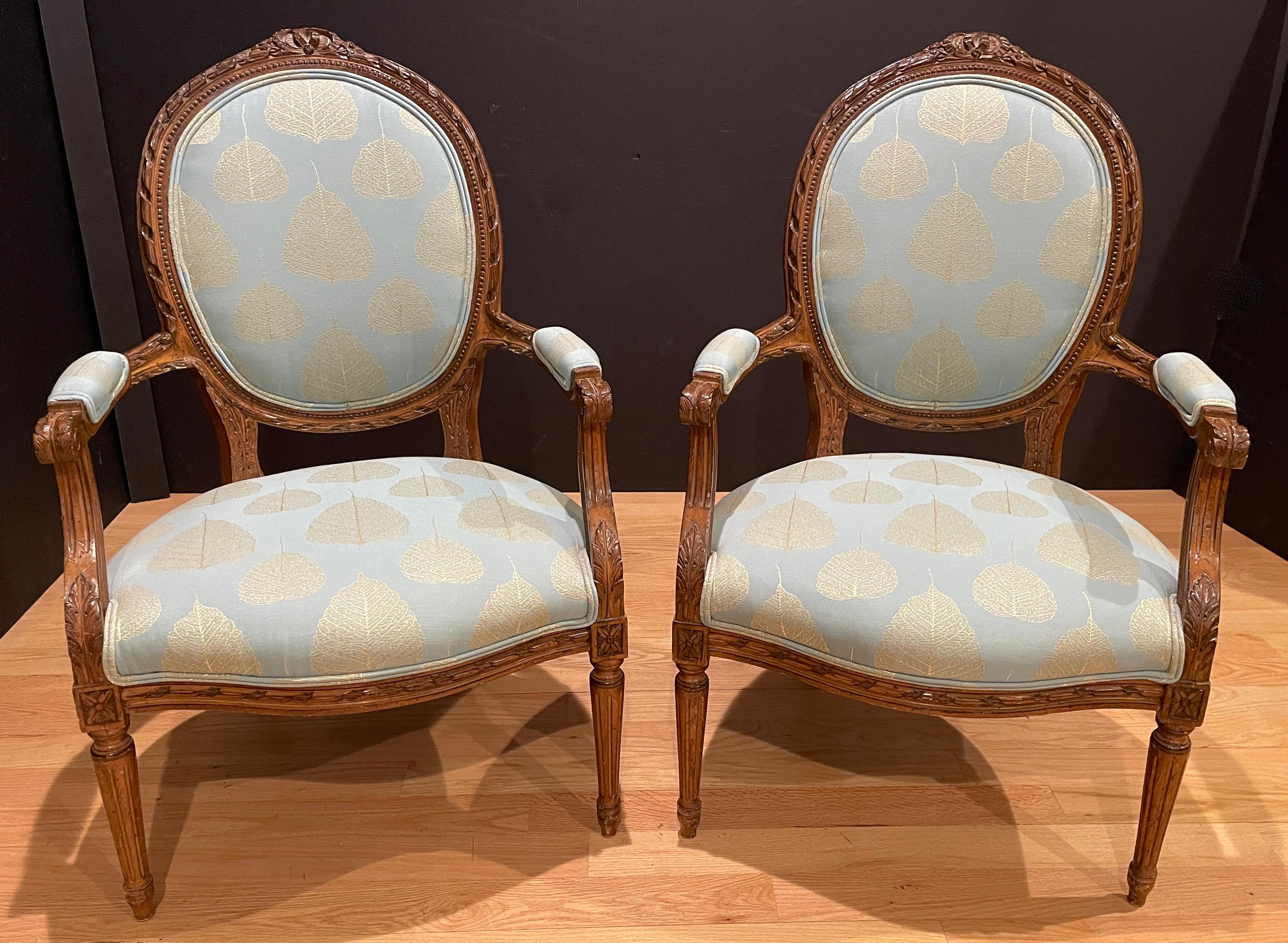 Pair of Louis XVI style carved walnut fauteuils. Bow and ribbon details. Blue and raised gilt fabric.