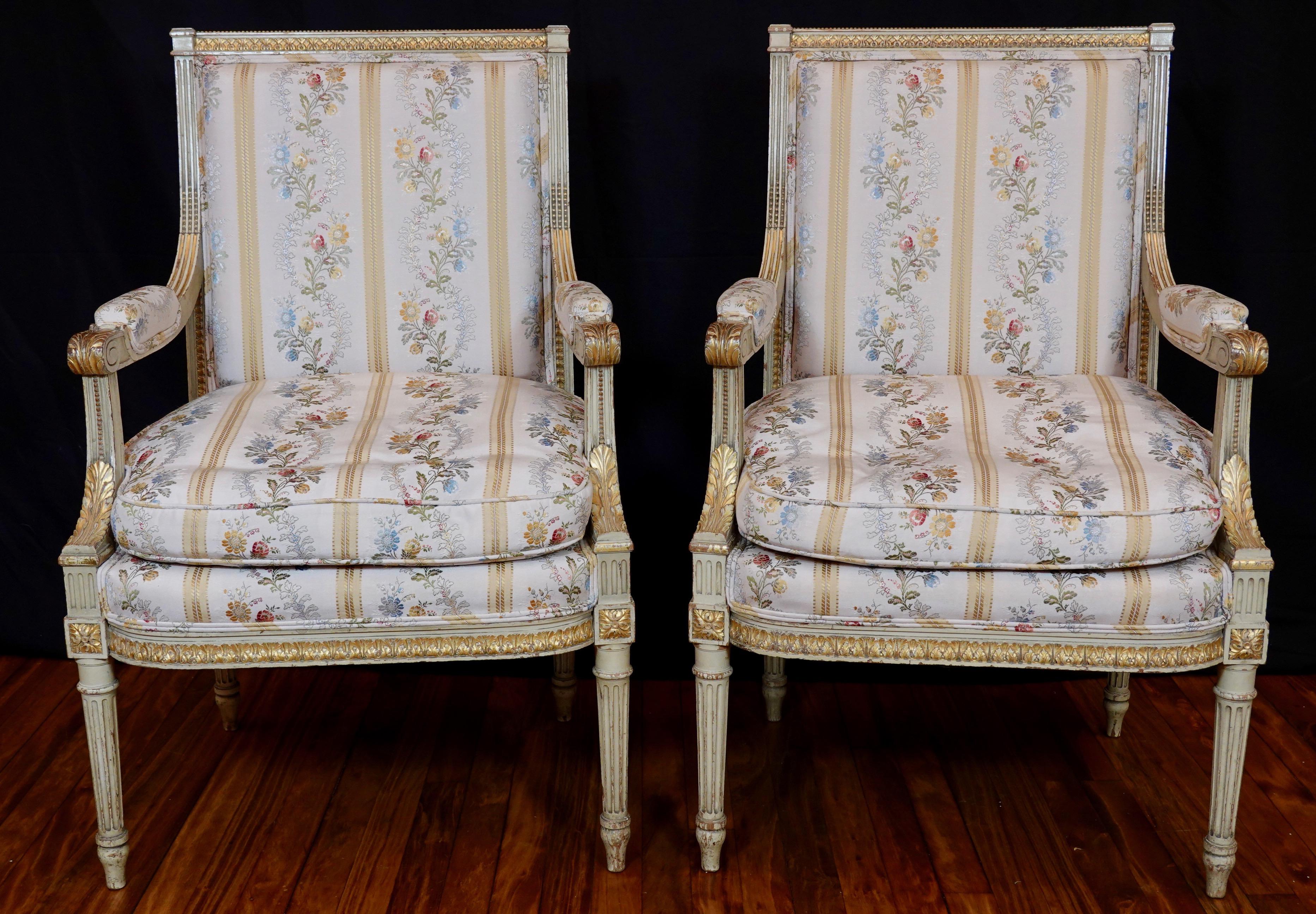 Pair of lovely Louis XVI style painted fauteuils with elegant silk lampas French fabric and double welt (early 20th century). The chairs are a light cream color with parcel gilt accents. Carved neoclassical ornaments include acanthus leaves, pearl