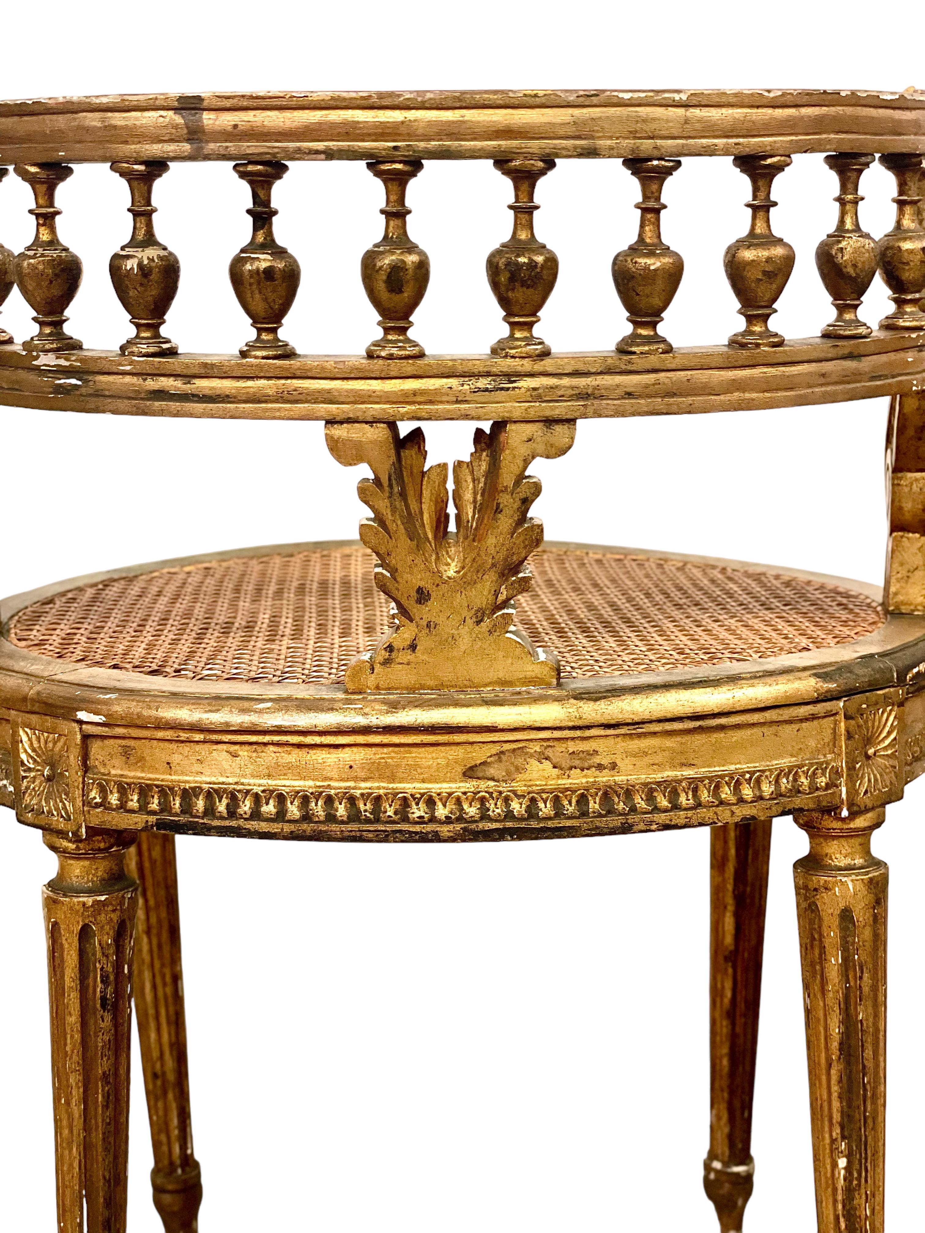 A pair of exquisite Louis XVI style vanity chairs, with lightweight, caned oval- shaped seats and extravagant wraparound gallery backrests. These chairs are wonderful examples of French craftsmanship, featuring intricate carving in the form of