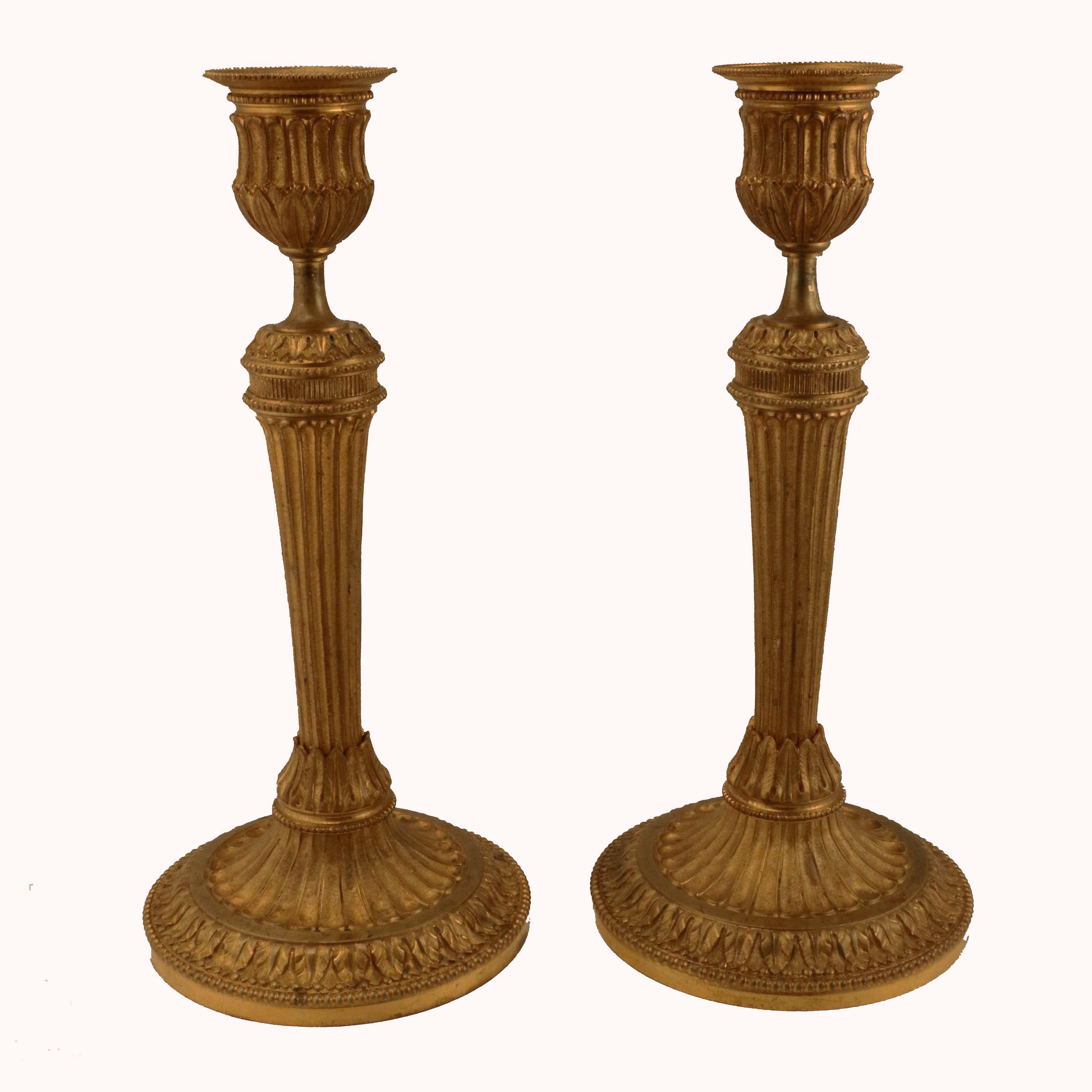 This pair are of Classic design and accomplished execution. The primary decorative motif is acanthus and beading. The base and column are reeded and have a matted finish. There are traces of gilding which give a sense of their age and quality.