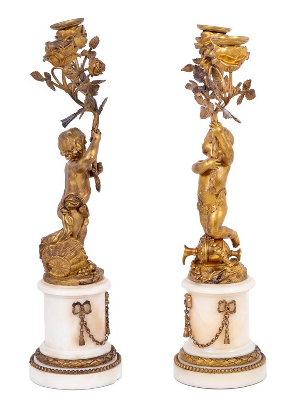 Coppia di candelabri figurati a due rami in bronzo dorato e marmo bianco in stile Luigi XVI, fine XIX secolo, ciascuno con un cherubino in piedi che sostiene un ramo gemello intrecciato di rose, su basamenti in marmo con decorazioni applicate. 16