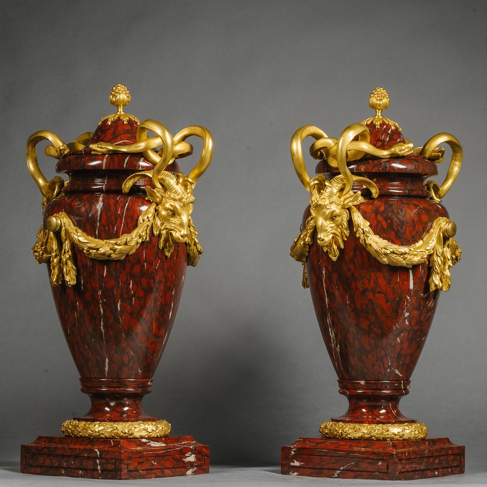Paire de grands vases et couvercles de style Louis XVI montés en bronze doré et en rouge griotte. 

Conçue dans le style néoclassique avec des poignées de serpent entrelacées au-dessus de masques de bélier reliés par des guirlandes d'acanthe. Ces
