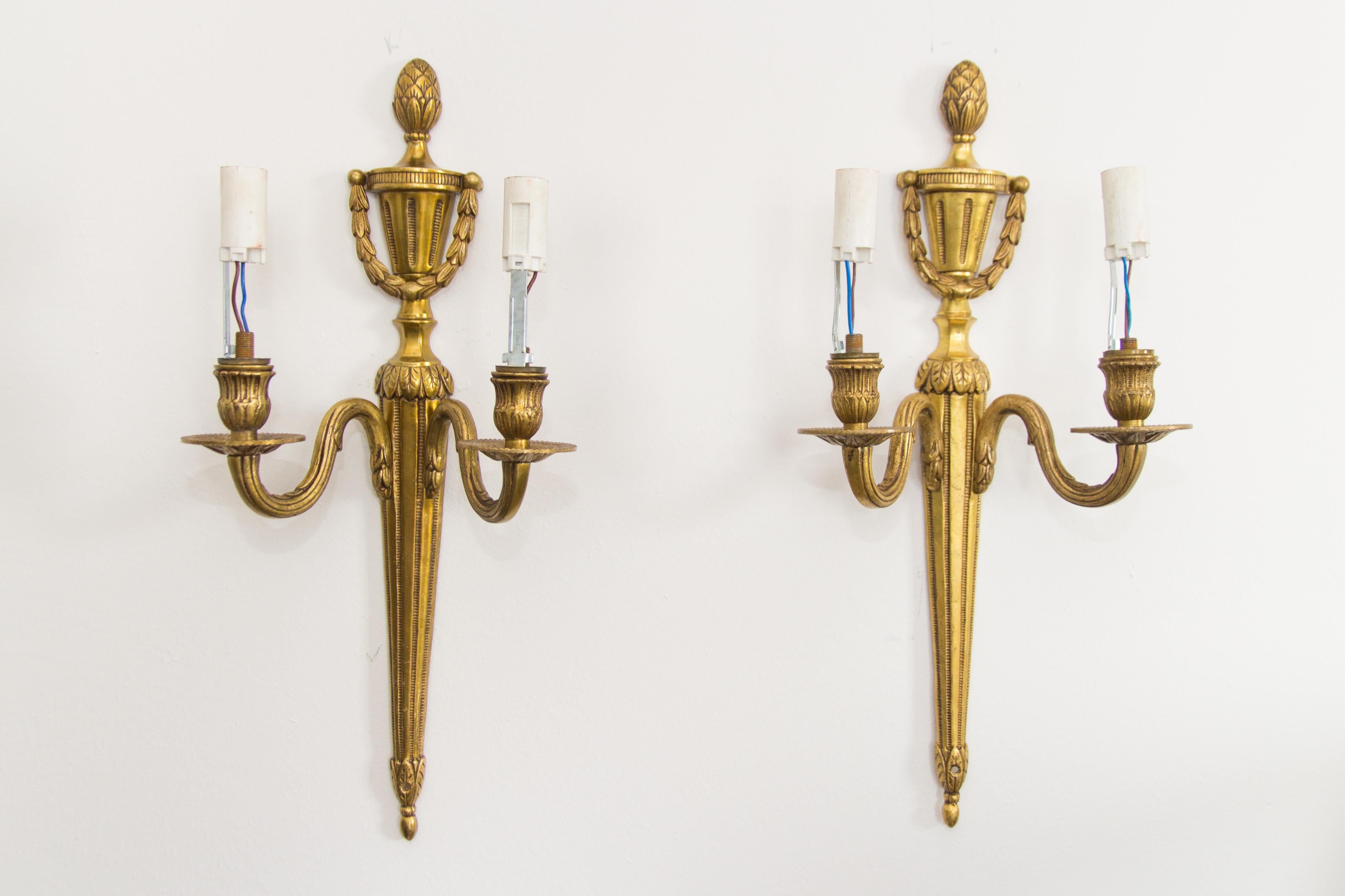 A pair of elegant French 20th century Louis XVI or neoclassical style gilt bronze electrified sconces. Each sconce has two arms and each arm has a E 14 socket with new wiring.