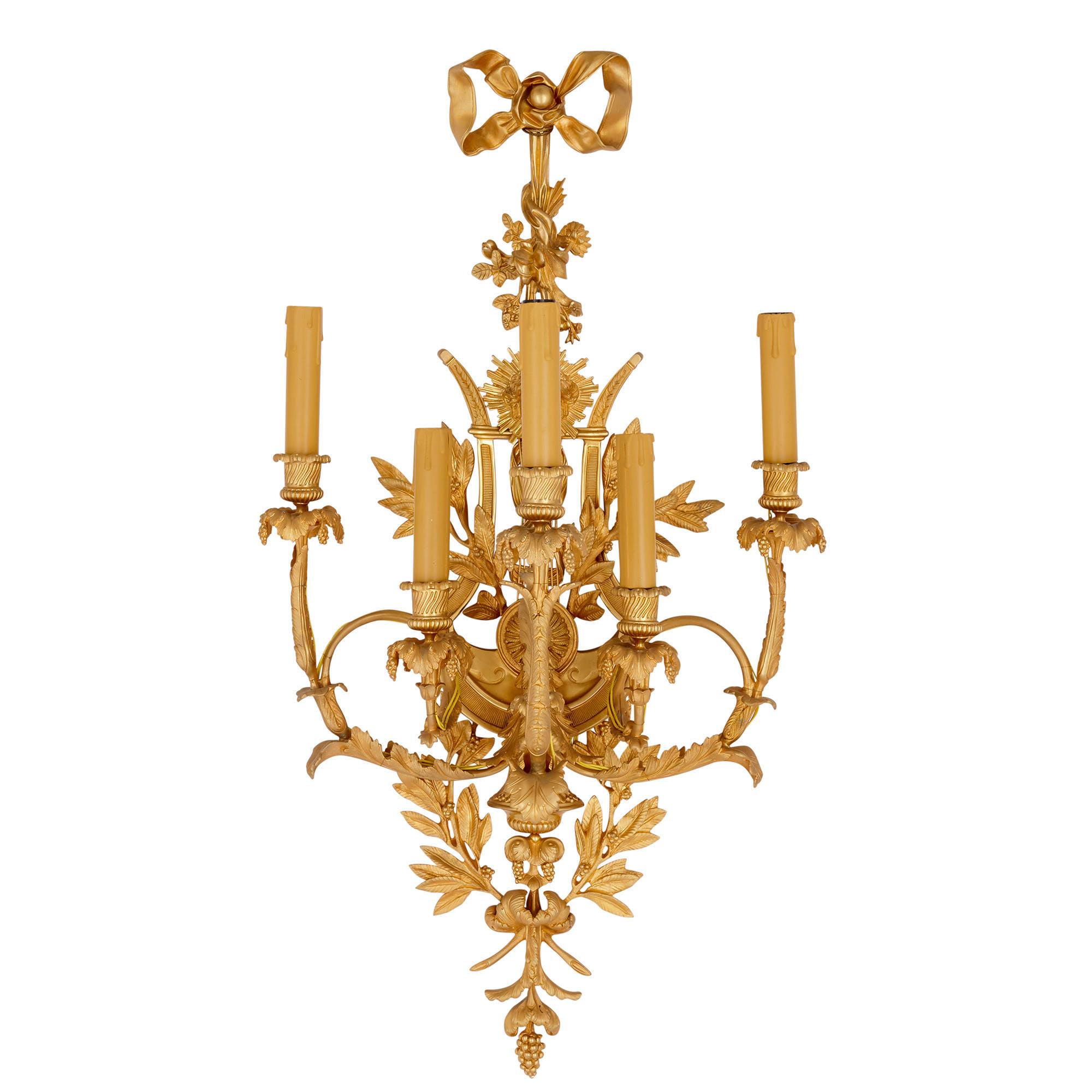 Pair of Louis XVI style gilt bronze sconces
French, 20th century
Dimensions: Height 94cm, width 49cm, depth 33cm

This pair of wall lights are superbly wrought in bronze, and feature exceptionally fine gilding. Each light is supported by a