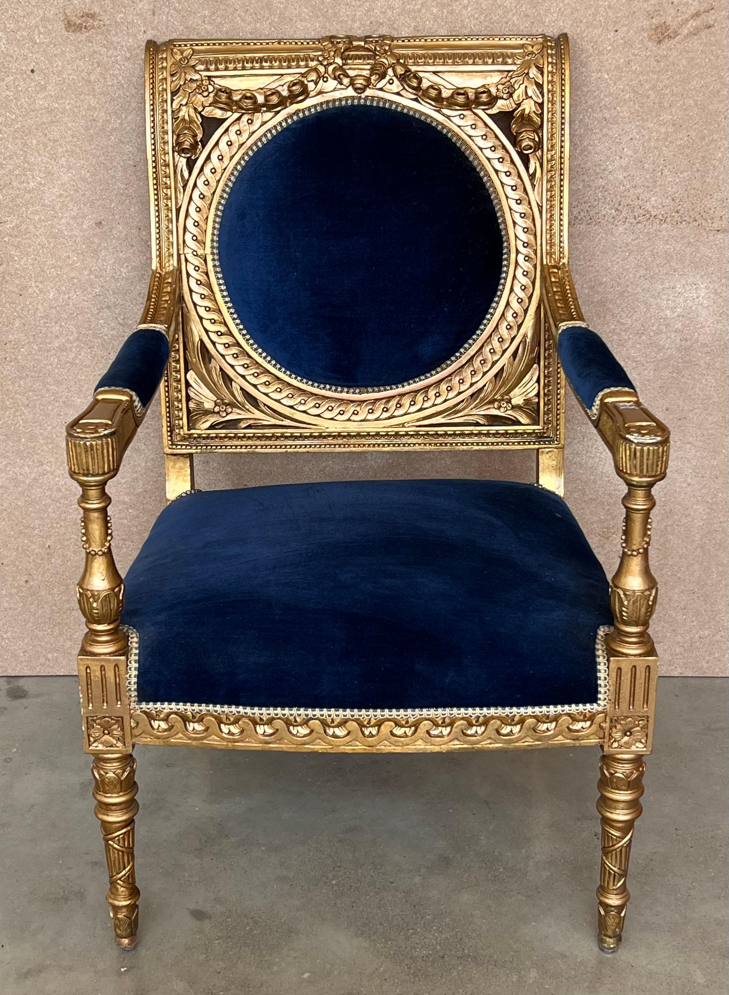 Louis XVI style armchair with medallion backrest.
 Elegantly carved and hand finished in a two tone patina, gilded or ecru, slightly aged. Made using traditional methods and materials. Upholstered in blue velvet.