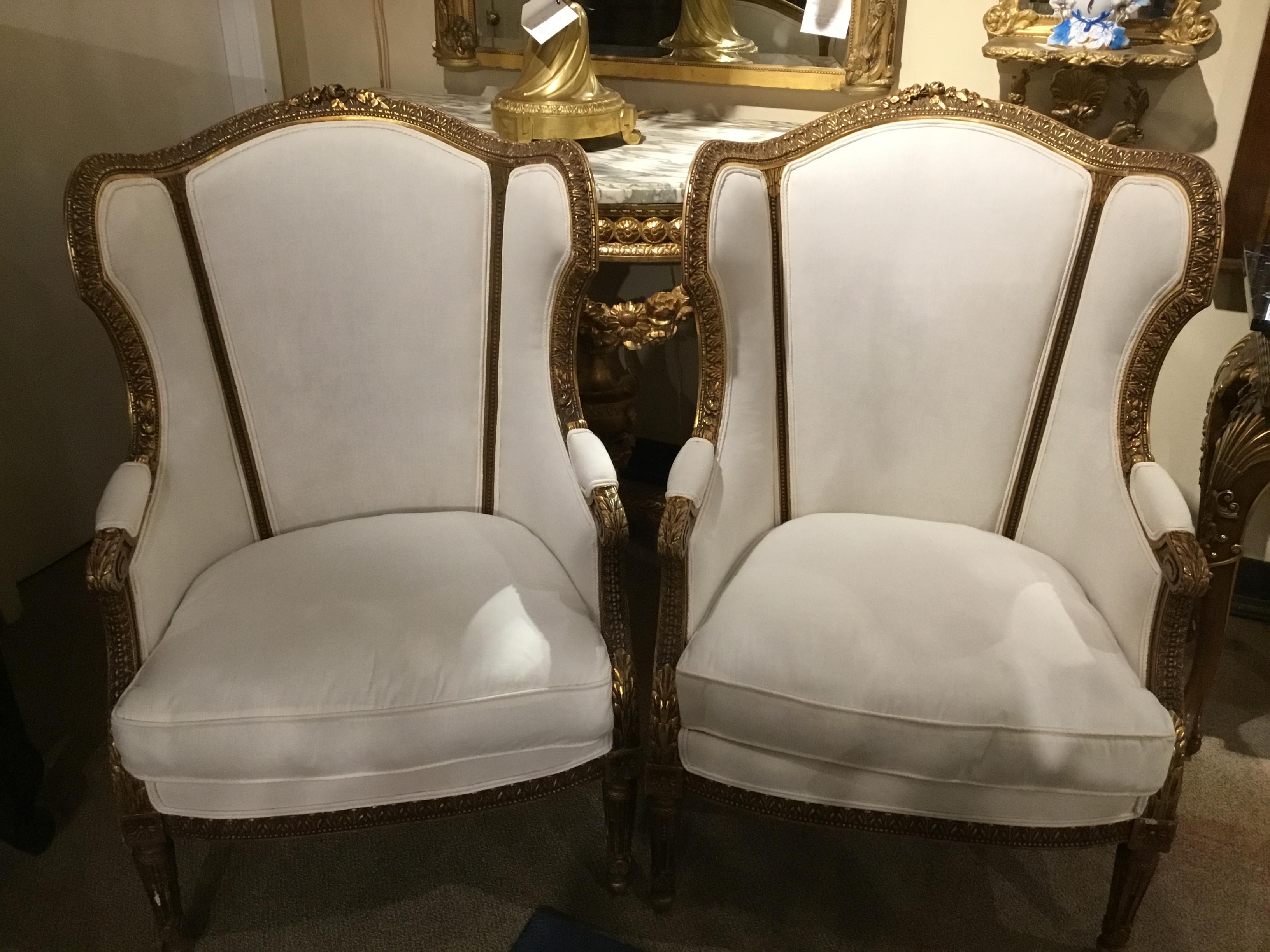 Bergères, each with trisected padded back surmounted by a floral crest, joined by downswept
Sides and scrolling padded arms to the cushioned seat, raised on stop fluted tapering circular
Legs ending in toupee feet.