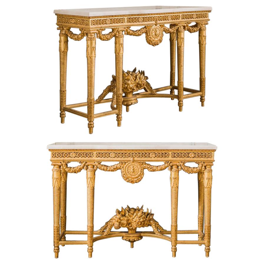 Pair of Louis XVI style giltwood consoles: Made as a one off by master craftsmen, elegantly carved and hand finished in a water gilded patina of 23.75-karat gold leaf. With 30mm Crema Marfil Beveled marble tops.