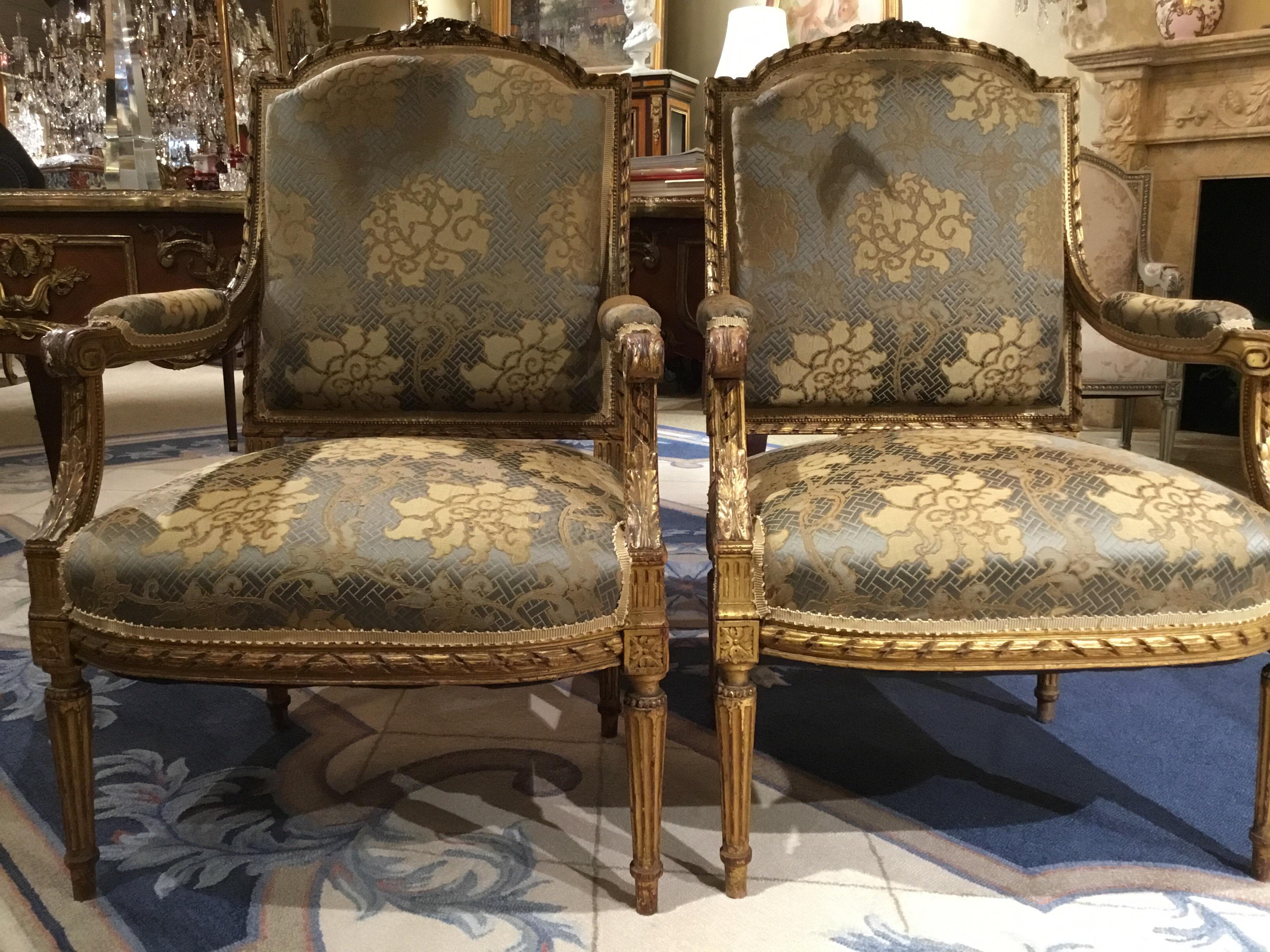 Exquise paire de chaises en bois doré de style Louis XVI, chacune avec un dossier rembourré
dos rectangulaire légèrement bombé surmonté d'une crête fleurie, relié par des
les bras rembourrés et sculptés en forme de feuillet sont reliés à l'assise