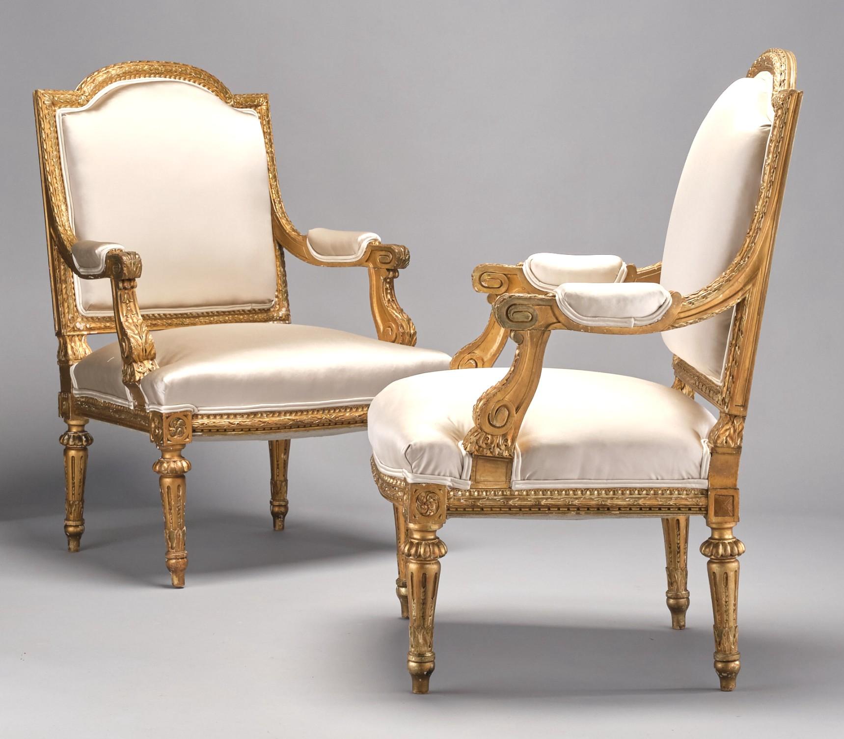 An attractive & very comfortable pair of giltwood fauteuils, both frames showing arched crest-rails with upholstered backs, sided by padded armrests terminating to carved grips over generously proportioned seats, decorated overall with carved &