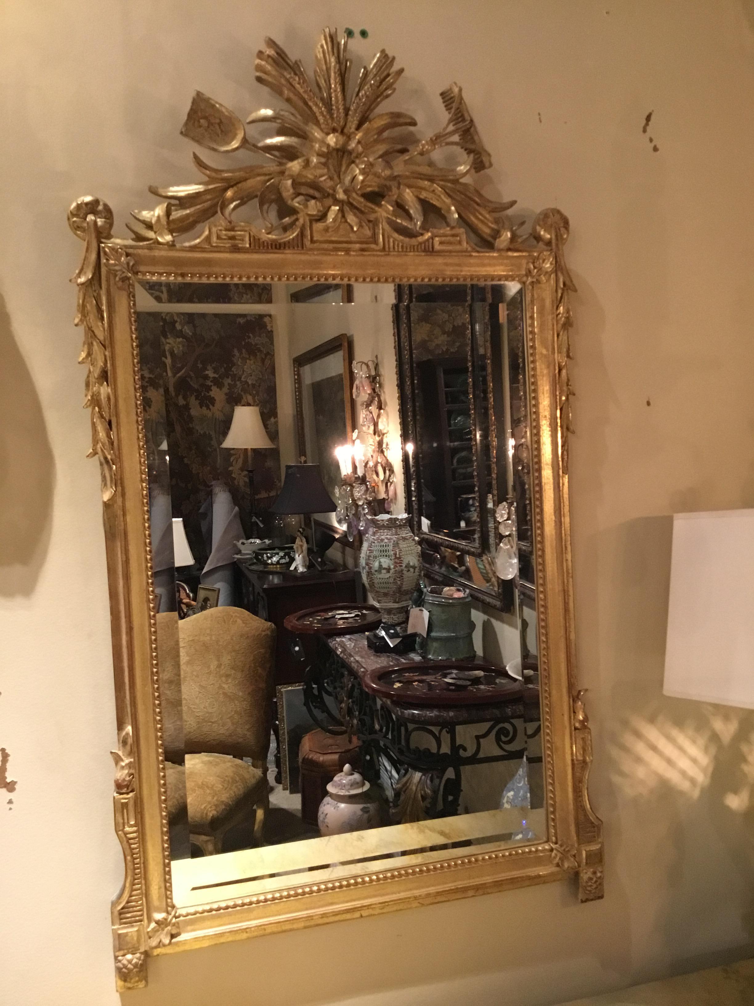 Pair of giltwood mirrors having a crest decorated with sheaves of wheat and garden
Trophies tied with bow knots, the sides with trailing leaves, the lower sides with pine cone carved
Feet, the molded surrounds with beaded liners, each set with a