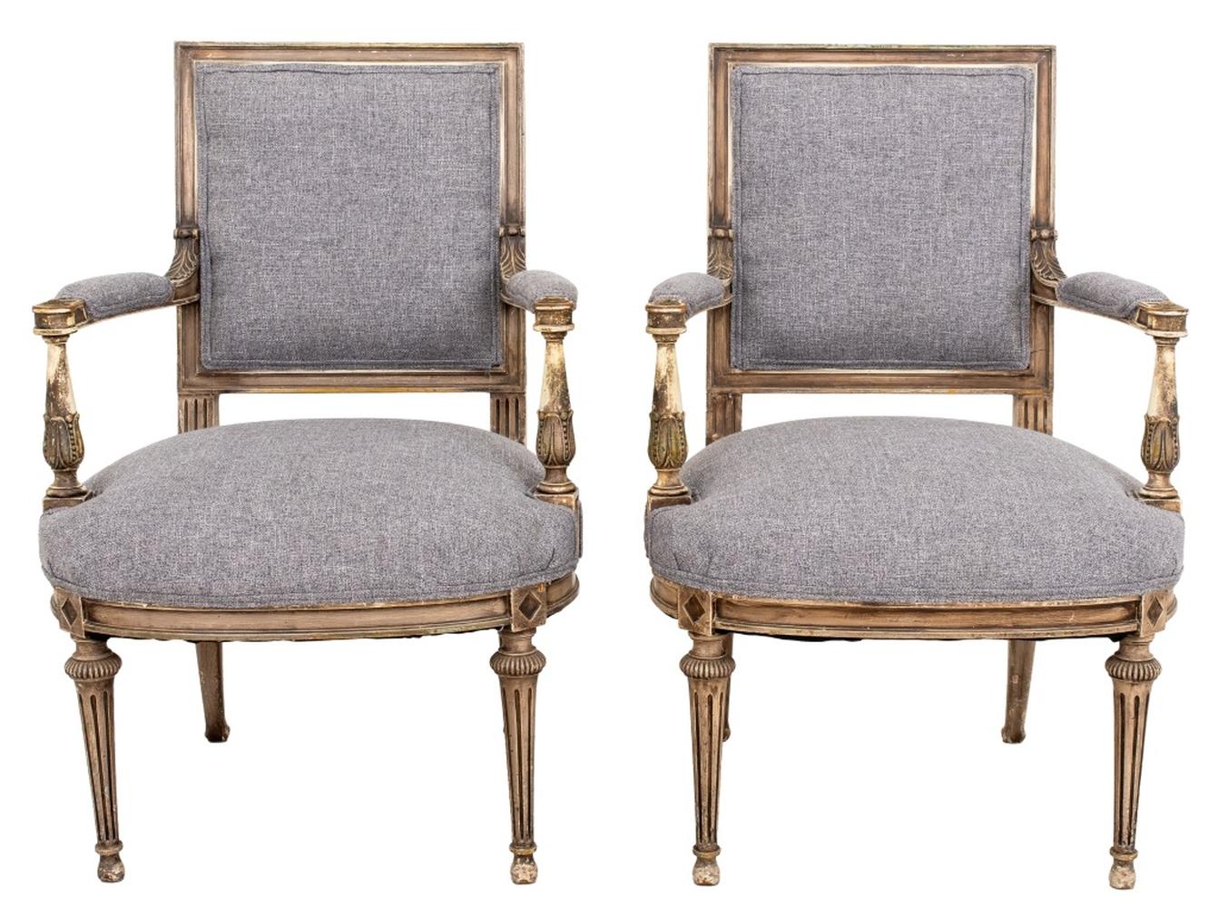 Paire de fauteuils anciens de style Louis XVI, peints en grisaille, datant de la fin du XIXe siècle. Chaque pièce présente un dossier rectangulaire, des accoudoirs gracieusement enroulés et une assise légèrement incurvée, recouverte de laine grise.