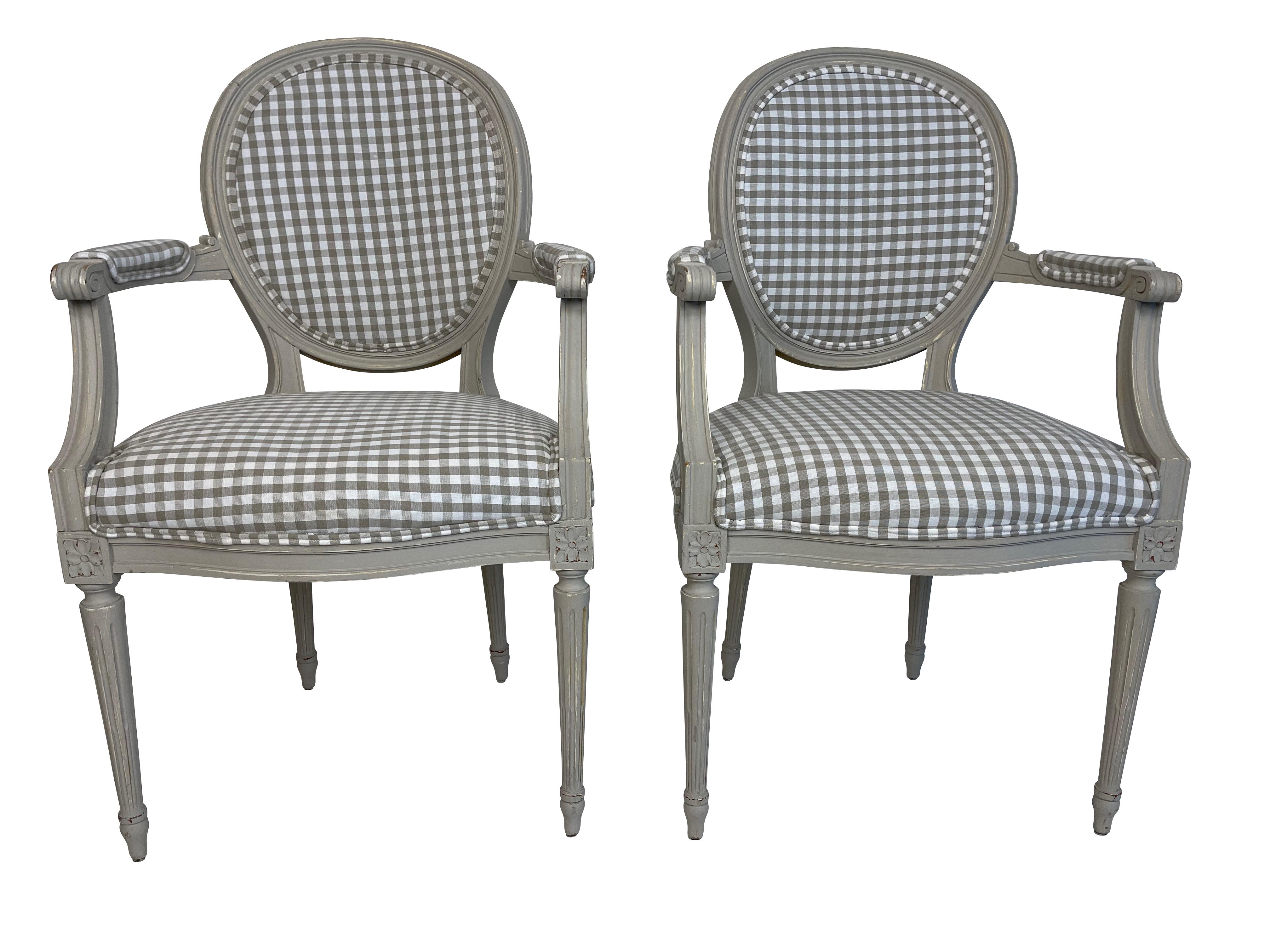Pair of Louis XVI grey painted fauteuils/armchairs newly re-upholstered in grey gingham fabric with oval backs, padded arms, reeded tapered legs with rosette decoration. Newly painted.