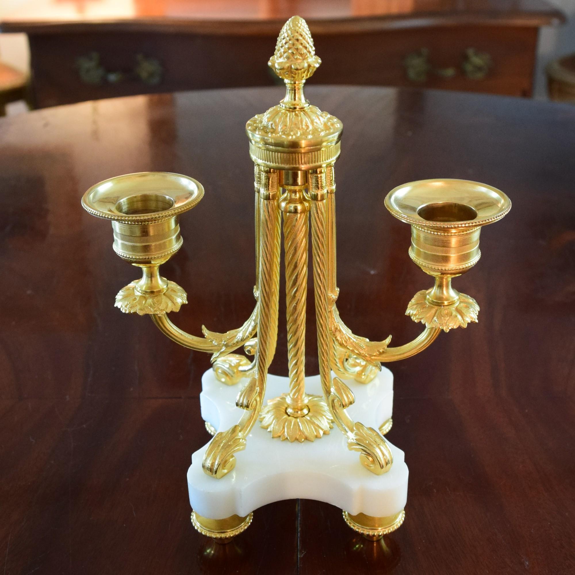 A Lovely Pair Of Louis XVI Style Ormolu and White Marble Two lights Candlesticks.

These ‘Bout de Table’ or End of Table Candlesticks are set in chiseled and gilded bronze, with white marble bases.
The arms of lights are decorated with laurel