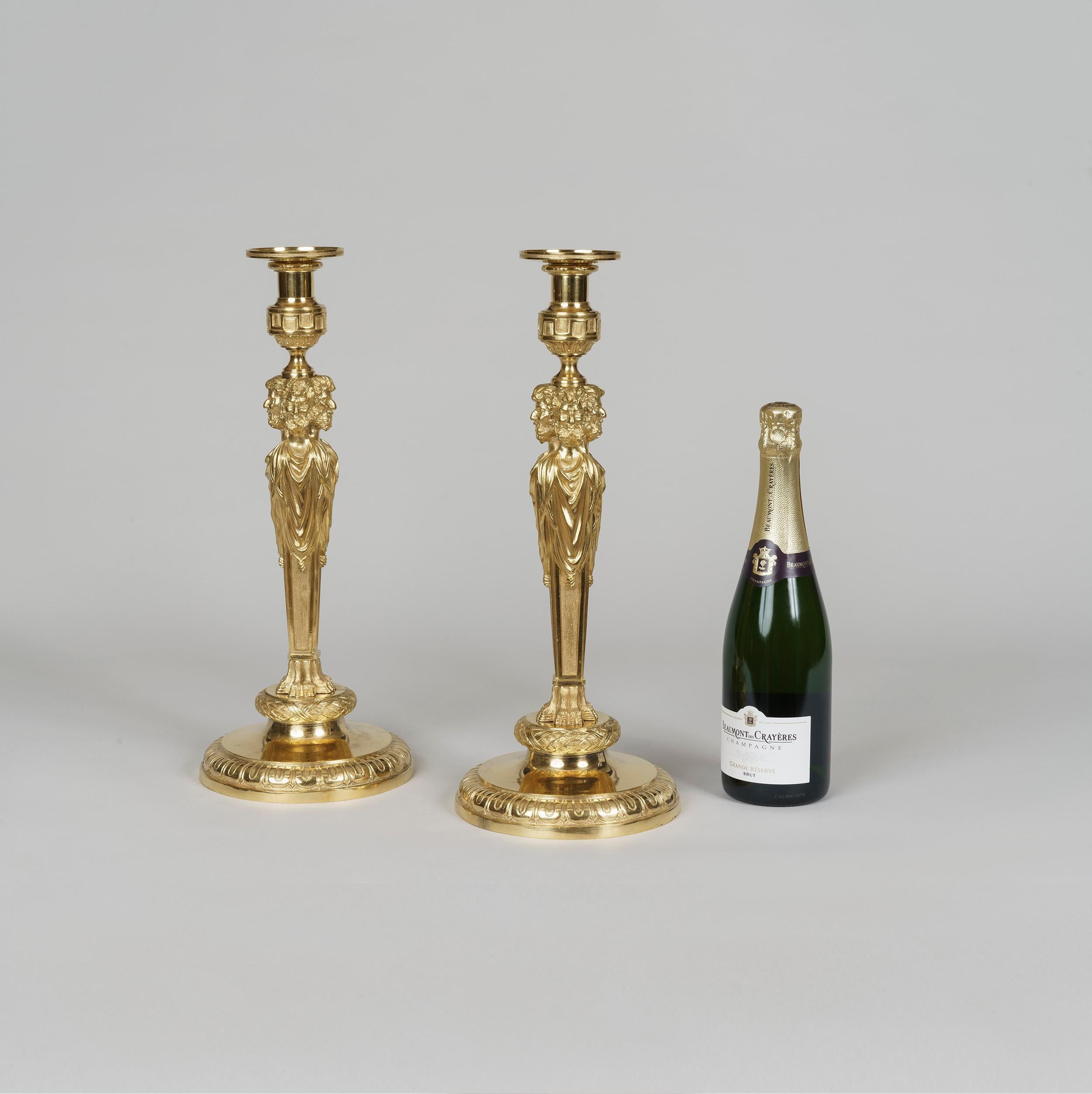 An important pair of Louis XVI style ormolu candlesticks
In the manner of Pierre Gouthière

Of substantial size and expertly cast in matt and burnished gilt bronze, the circular pedestal base having decorated rims; the rectangular shaft modelled