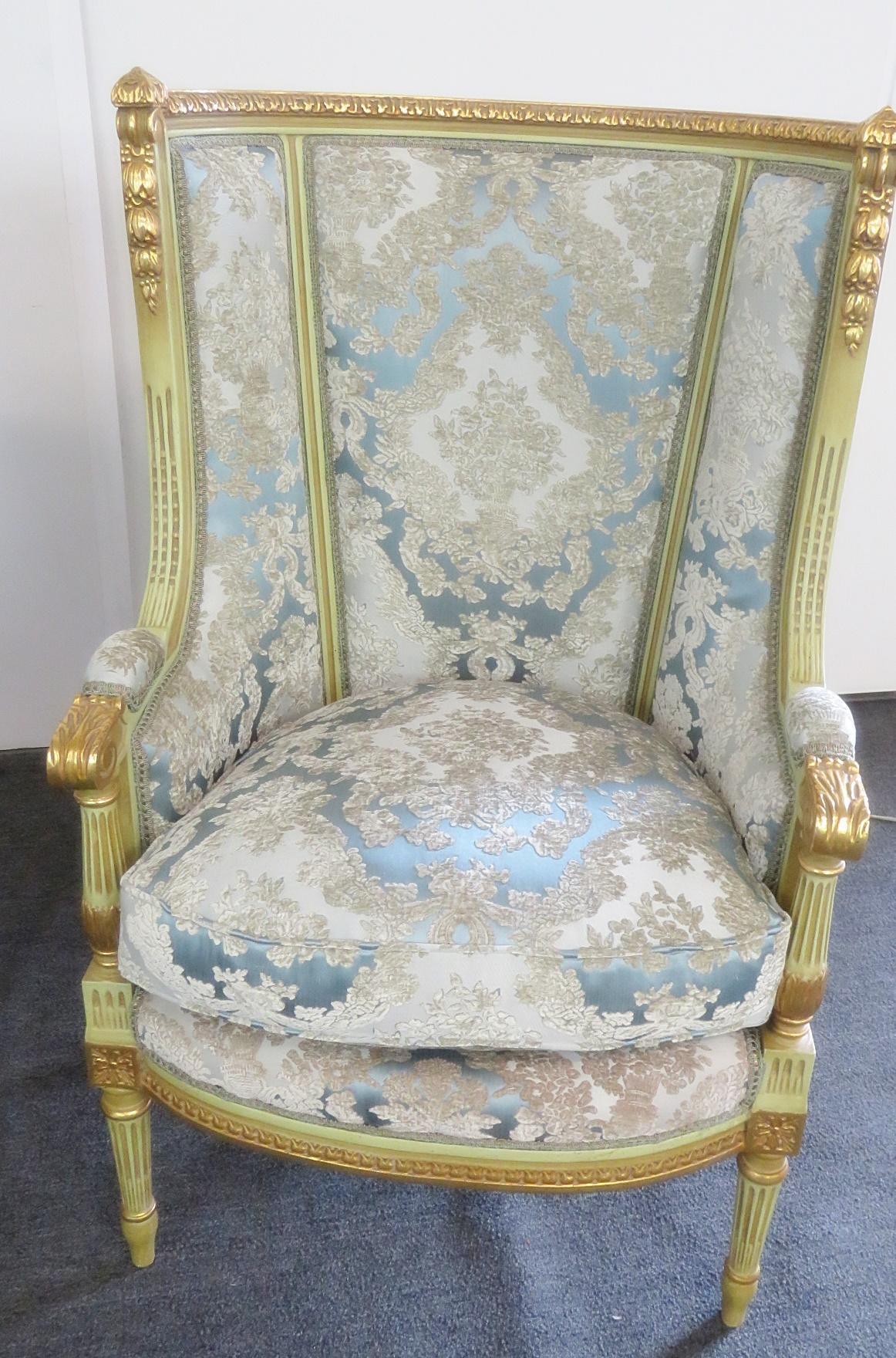 Pair of Louis XVI style paint decorated wing back chairs with gilt accents and textured upholstery.