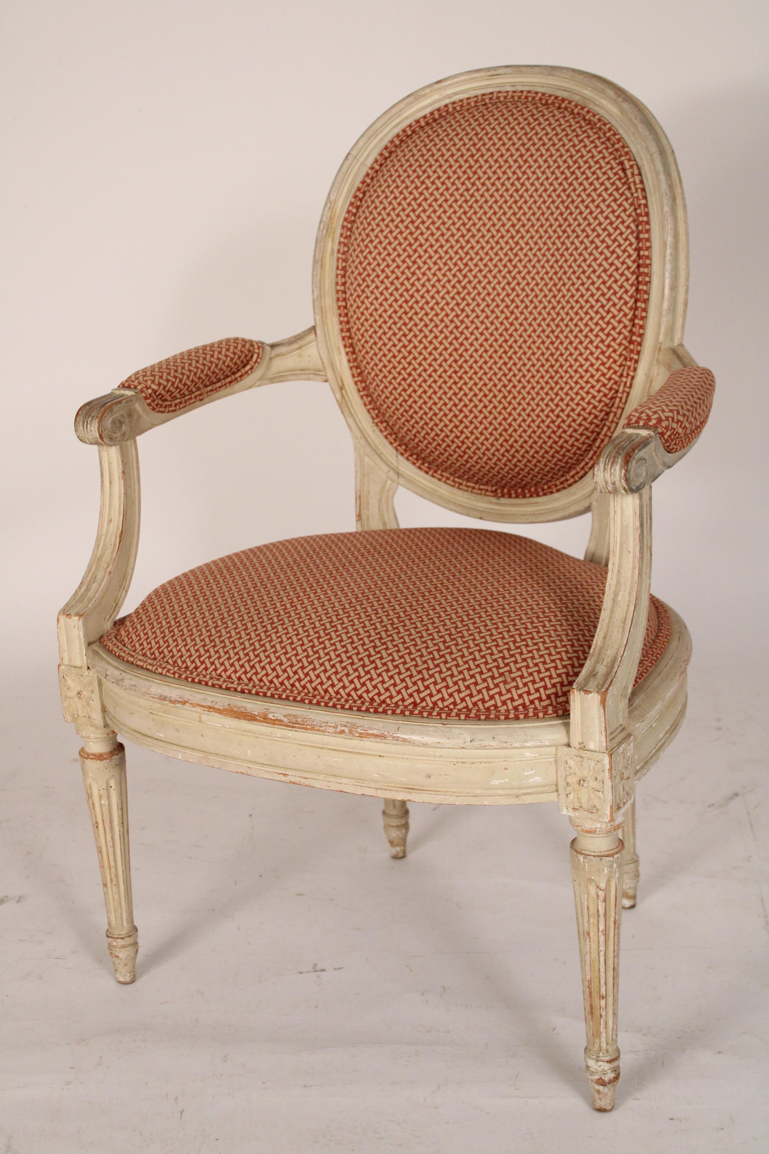 Paire de fauteuils peints de style Louis XVI, vers 1930. Le dossier est ovale et tressé, les accoudoirs sont rembourrés et les pieds cannelés sont tournés et effilés. 