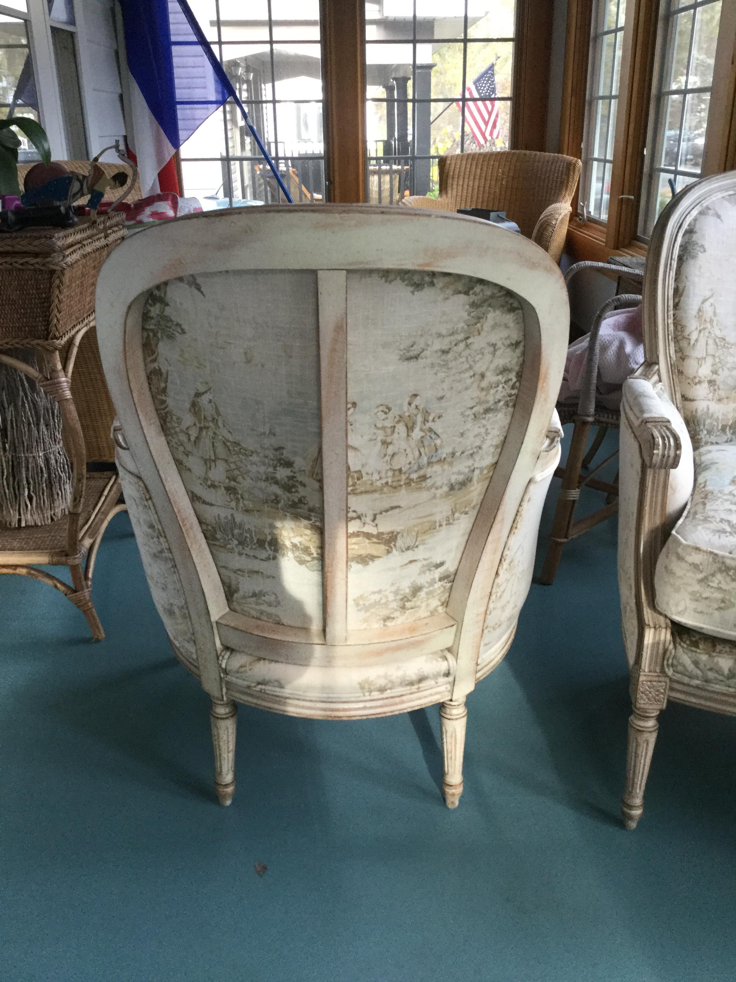 Stunning pair of French painted bergère chairs. These chairs feature beautifully carved frames with an antique white finish. Typical of Louis XVI, the legs are fluted and the back is rounded. The toile upholstery is in shades of very soft green,