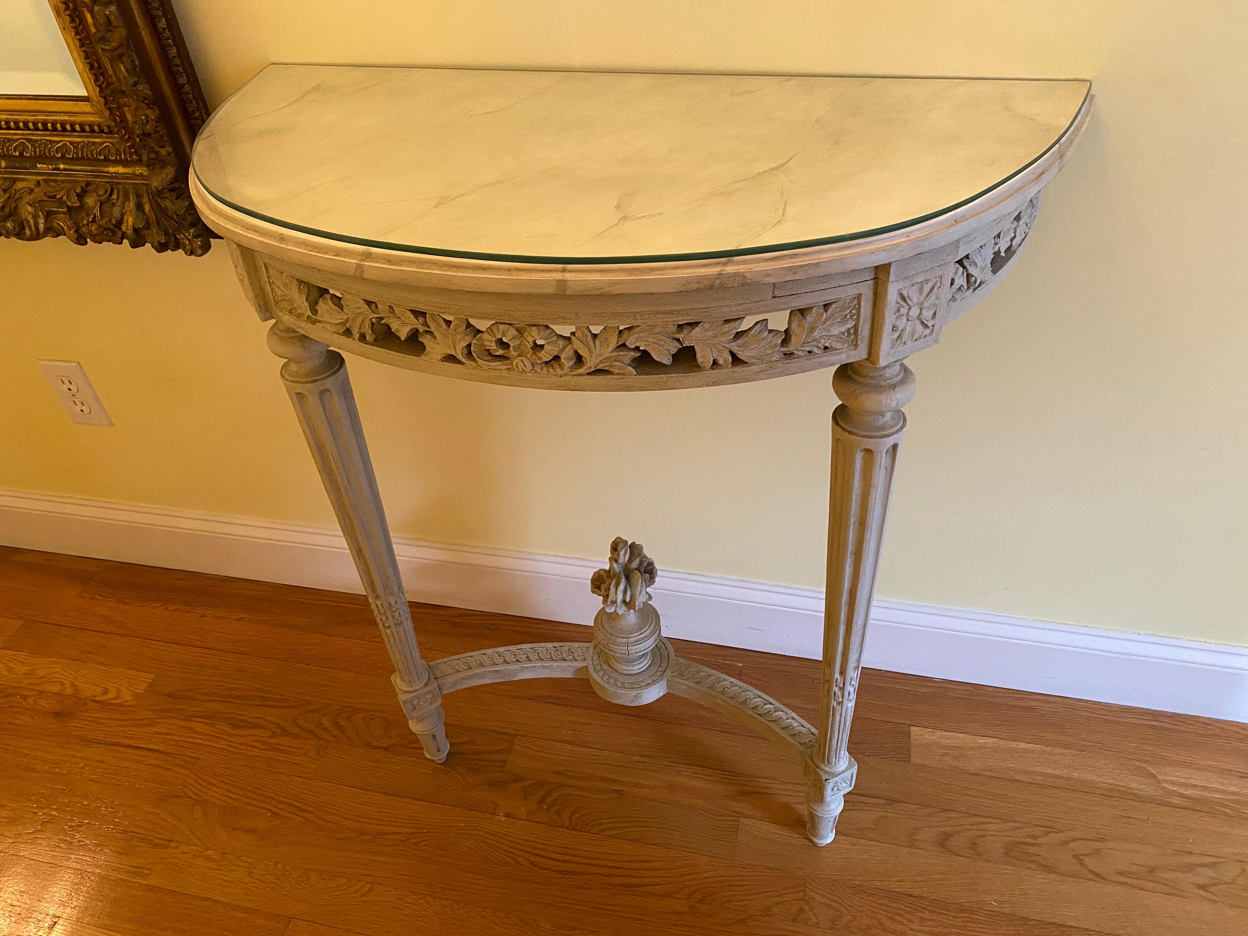 Pair of Louis XVI style painted demi lunes with faux bois marble tops. A lovely pair of diminutive demi-lunes with fine carved details and faux painted marble tops and additional protective glass tops. Base and top made of carved wood, base is