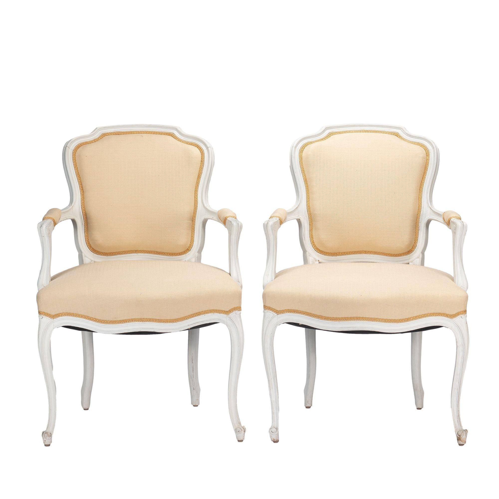 Pair of generously scaled Louis XVI style carved hard wood fauteuil with upholstered back panels, arm caps, and seats. The hardwood frames are finished in a white stain. 
American, Academic Revival, 1910-30.

Dimensions: 25” W x 27” D x 37-3/4”