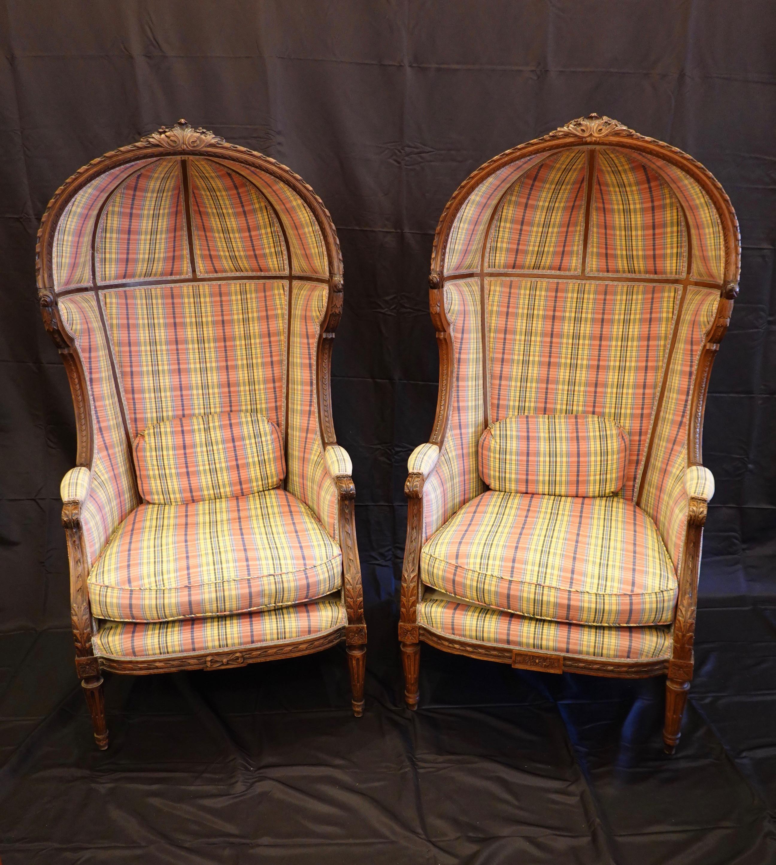 Pair of walnut Porter chairs in the Louis XVI style featuring hand carved acanthus leaves on the crest rail and arms, tapered legs with cabled fluting, central bow on the seat rail and other neoclassical details (circa late 19th century). The