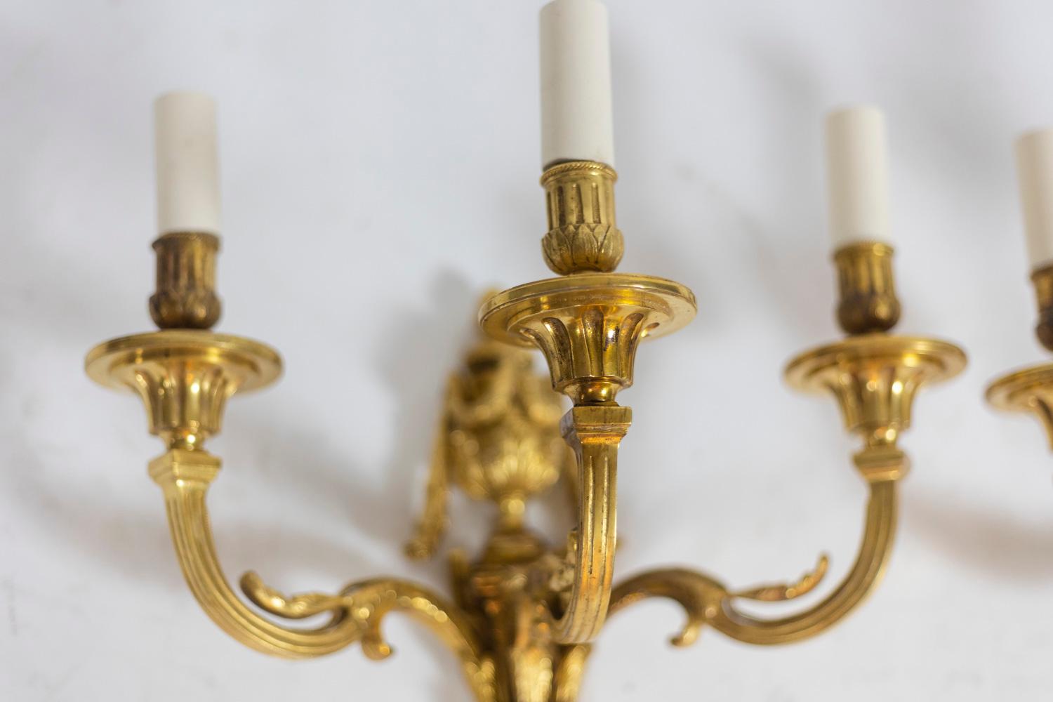 Pair of Louis XVI style sconces, with three gilt bronze lights, decorated with leaves, a fire pot, a garland and sconces.

French work realized circa 1880.