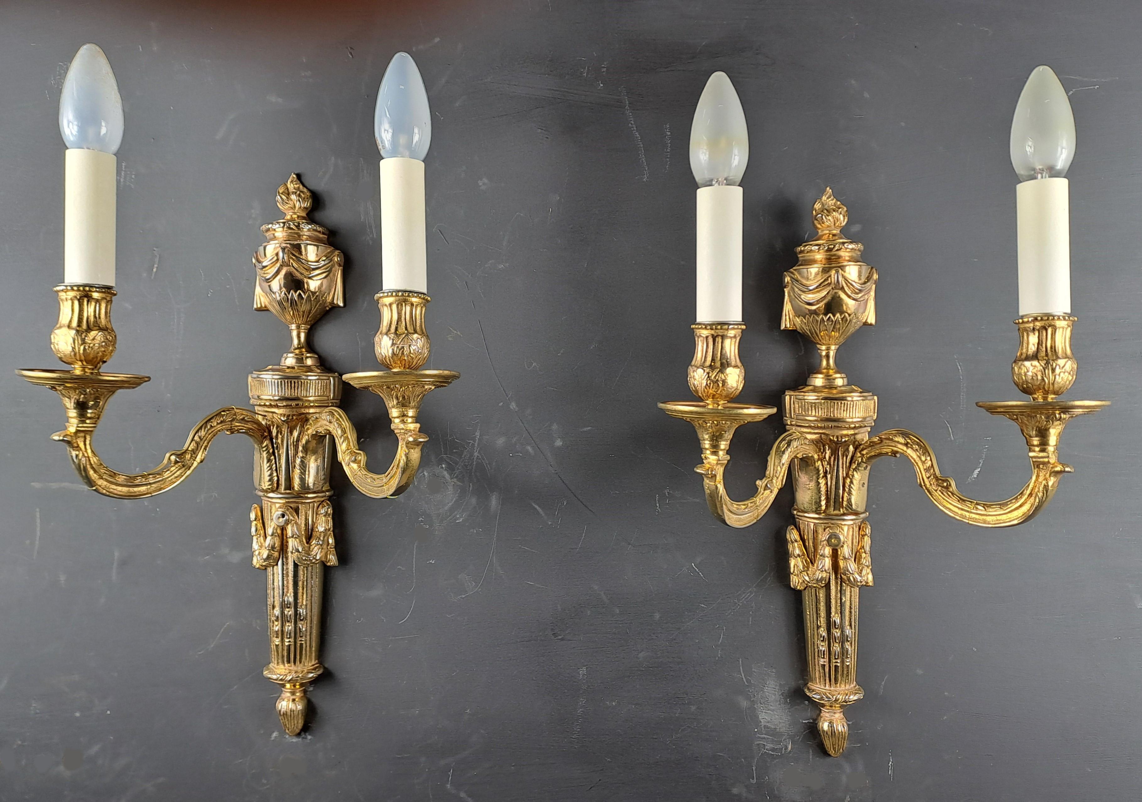 Pair of Louis XVI Style Sconces in Gilt Bronze with two arms of light.

Beautiful classic decor including a fire pot and garlands.

Work from the end of the 19th century.

Very good condition,  electrification completely redone by our workshop. EU