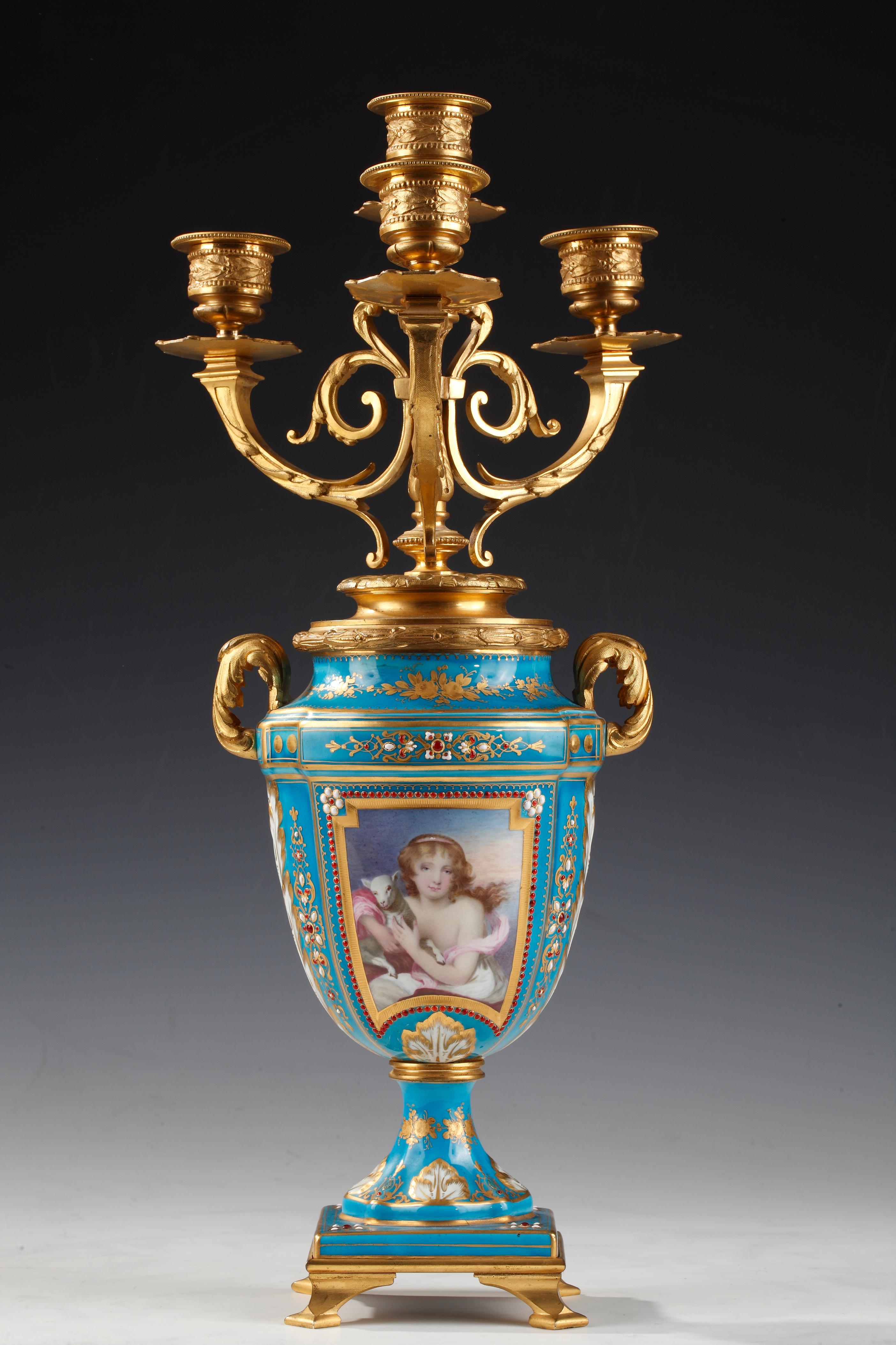 Jarrones de porcelana turquesa de estilo Luis XVI con decoración policroma al estilo de la Manufactura de Sèvres. Cada cara está adornada con un retrato femenino con un perro o una oveja y la otra con un paisaje en porcelana. El conjunto está