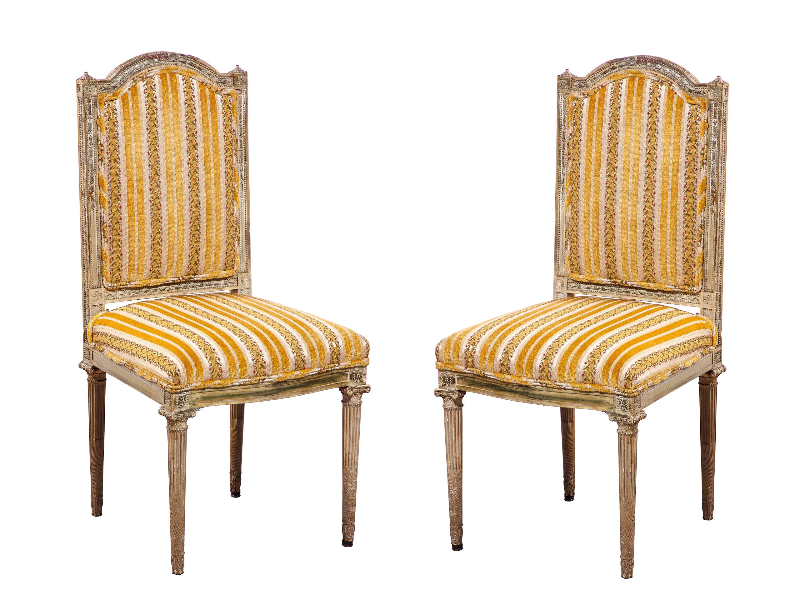 The fine pair of Louis XVI side chairs with an intricately carved frame surrounding an upholstered back and seat with fluted legs, the whole having original paint in a lovely faded patina.