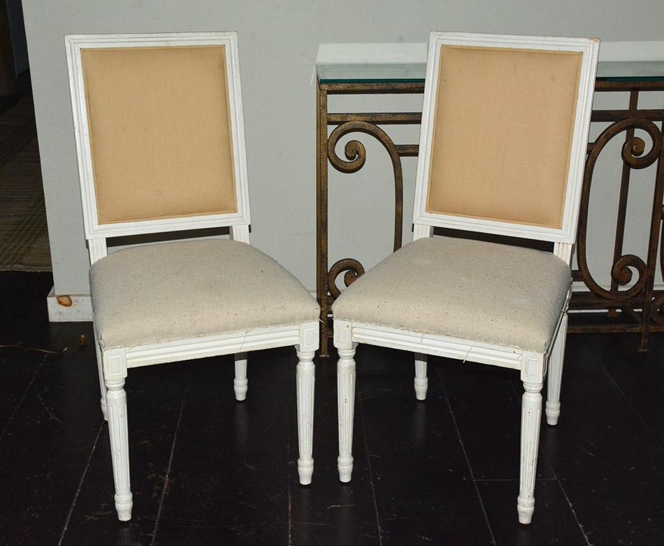 Pair of French Louis XVI style side dining chairs with wood frames in white painted finish, fluted leg and cubic blocks decorated with florets. Appropriate for dining or desk chairs in modern of traditional Swedish Gustavian Style decor.