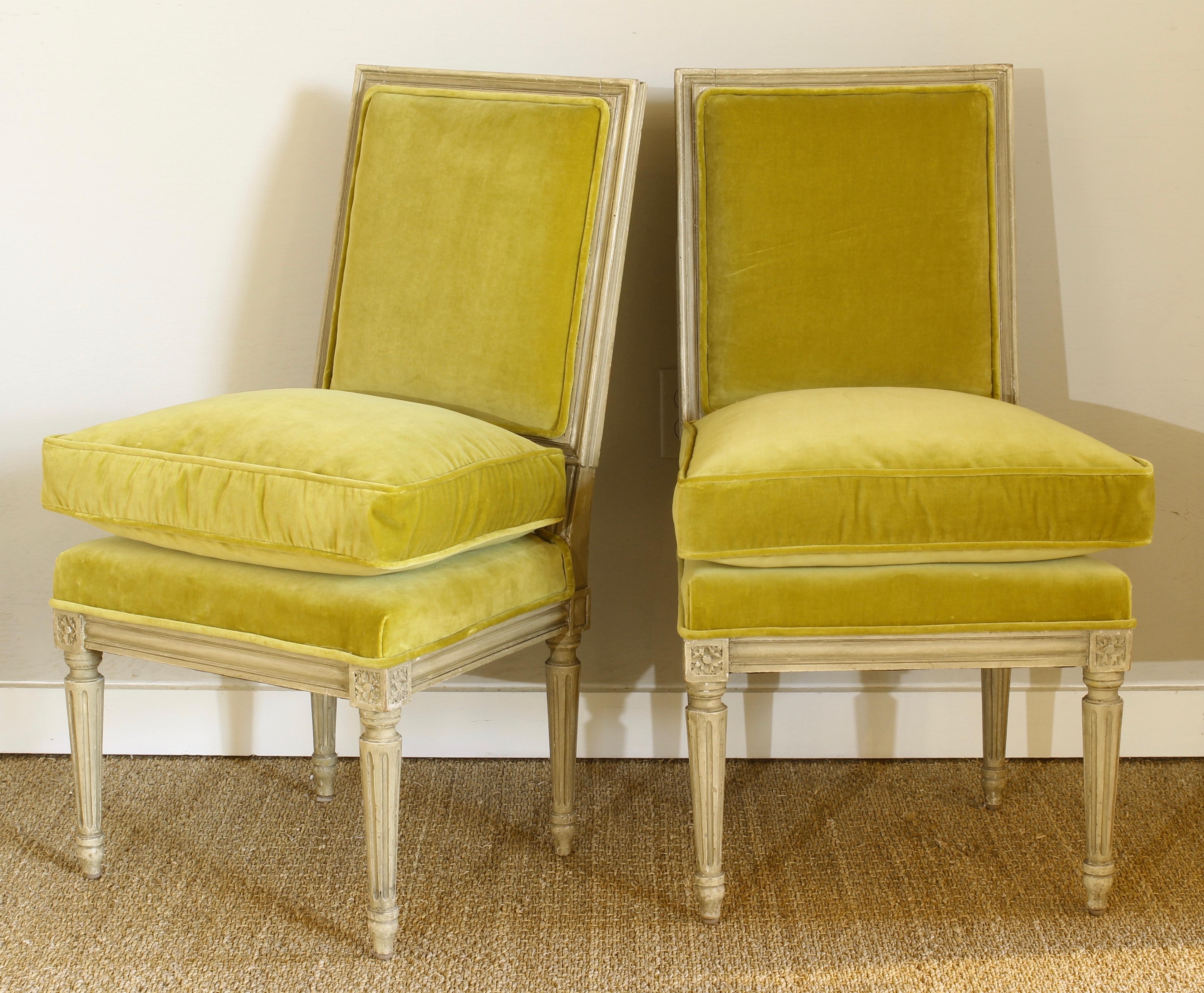 A lovely pair of small late 19th century. Louis XVI style painted slipper chairs recently upholstered in a lustrous chartreuse green velvet.