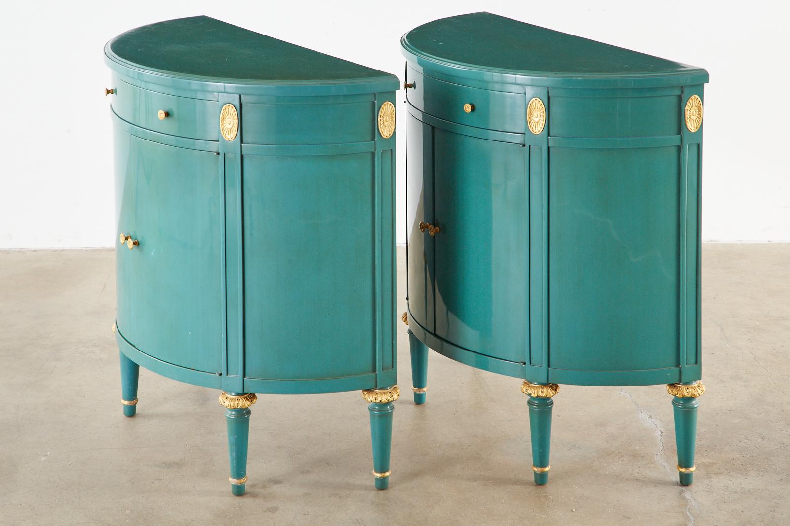 Bespoke pair of lacquered cabinets having a demilune form. Featuring a turquoise blue-green finish with gilt rosettes and acanthus on the legs. Each cabinet has a drawer on top of two doors opening to a large storage area. The pulls have gilt bronze