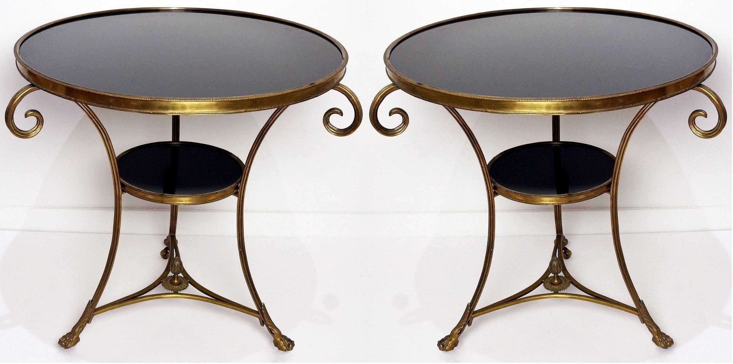 Elegant pair of guéridons. The tables present a French circular variegated black marble top within an ormolu border. Each piece rests on three inward curved bronze legs terminating in hoof feet. The legs are connected by a concave-sided tri-form