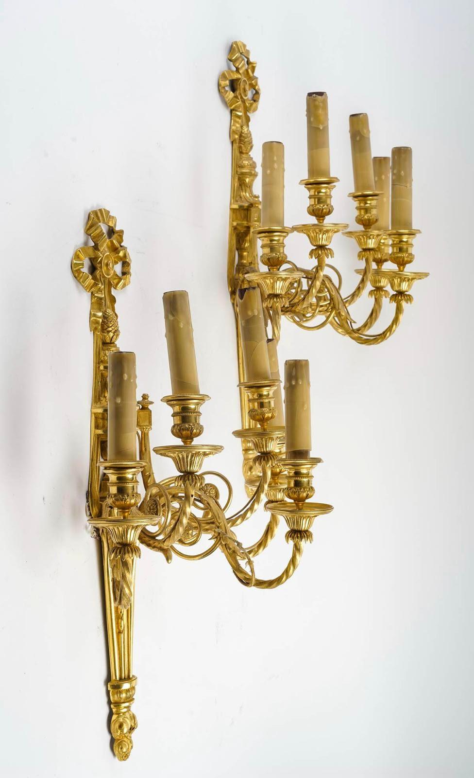 Pair of Louis XVI style wall lights in chased and gilt bronze.

Pair of Louis XVI style wall lights in chased and gilt bronze, 5 arms.
W: 40cm, H: 60cm, D: 26cm