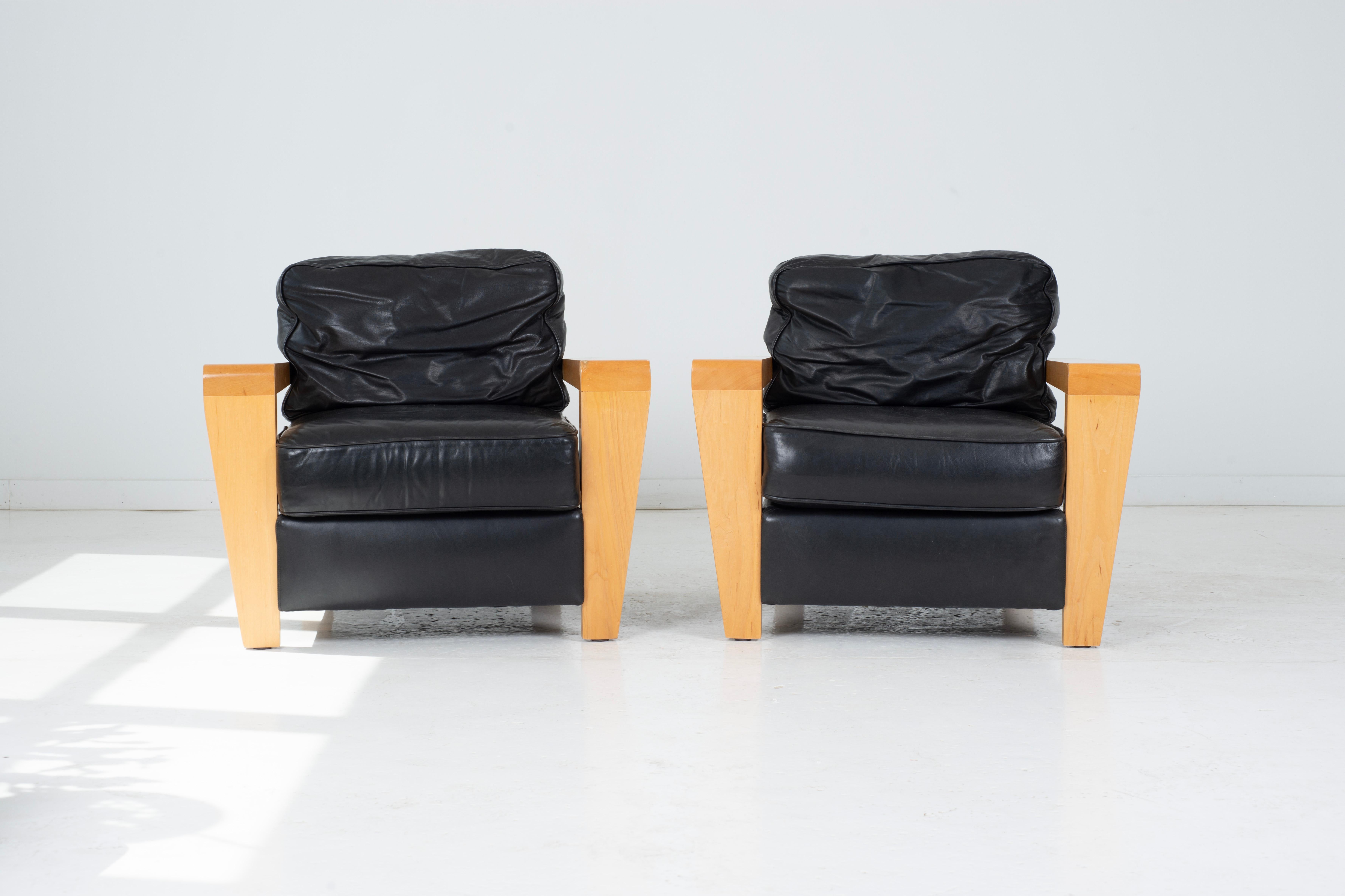 Introducing a striking pair of contemporary black leather lounge chairs and ottomans, designed exclusively for Thayer Coggin. These sophisticated pieces showcase the beauty of original, nicely worn leather, exuding a timeless charm and character