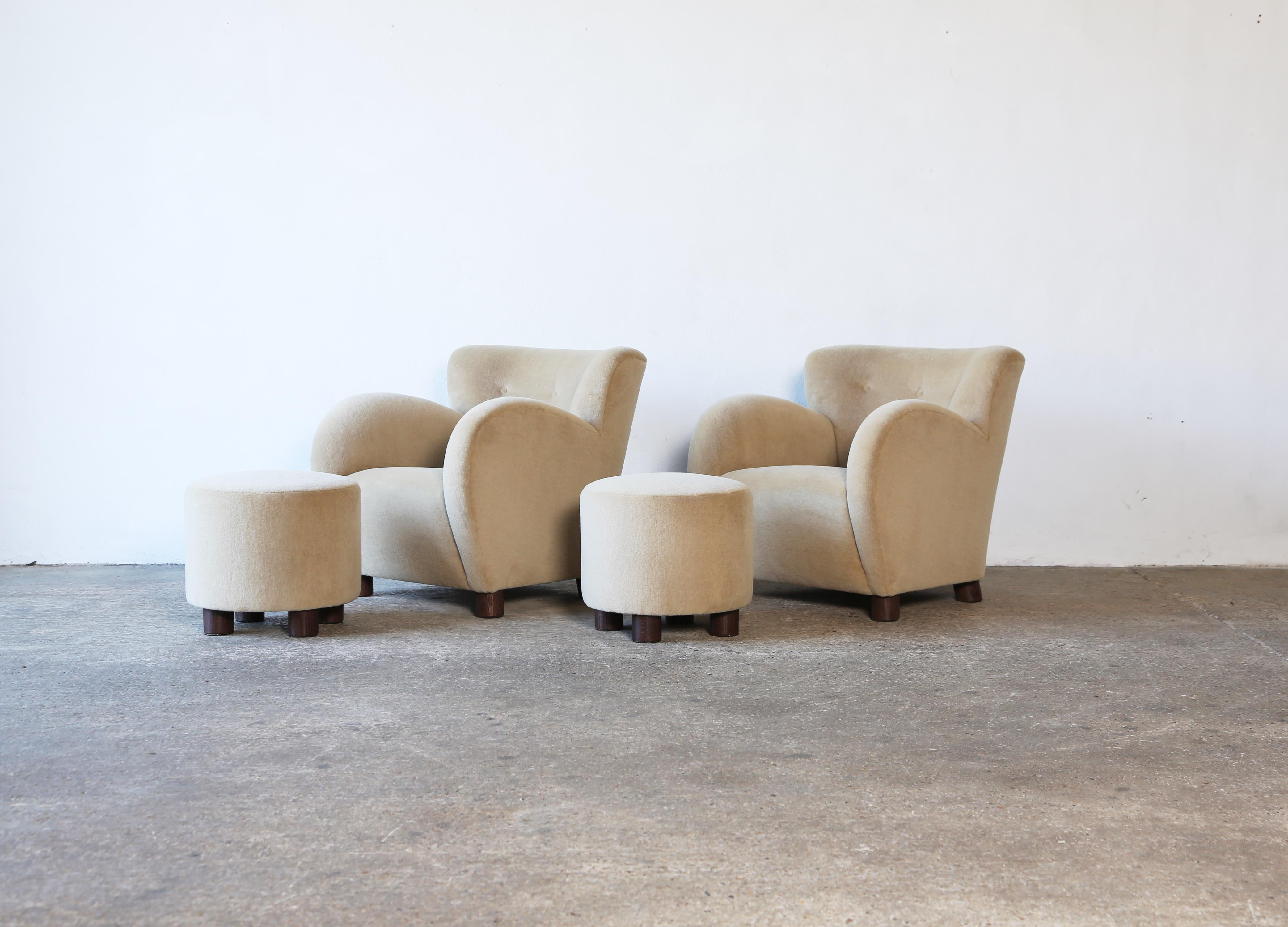 Superbe paire de fauteuils modernes à accoudoirs ronds et ottomans. Structure en hêtre fabriquée à la main, assise à ressorts et nouvellement tapissée d'un tissu en pure laine d'alpaga beige/sable de première qualité, avec des pieds en chêne massif.
