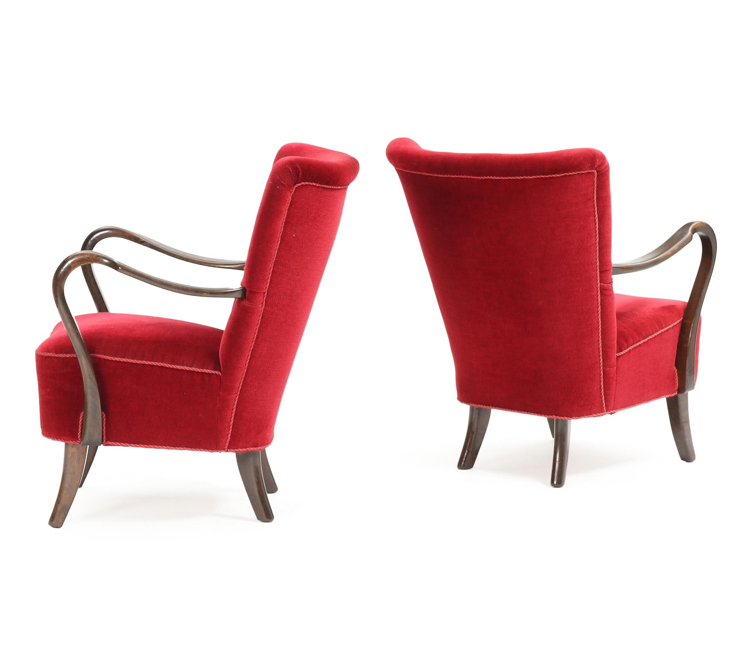 A pair of Danish modern easy chairs with stained beech frames by designer Alfred Christensen. These chairs are distinctive with their curved wood open arms. Upholstered in red velour in good condition. Manufactured by Slagelse Møbelværk in 1940s.