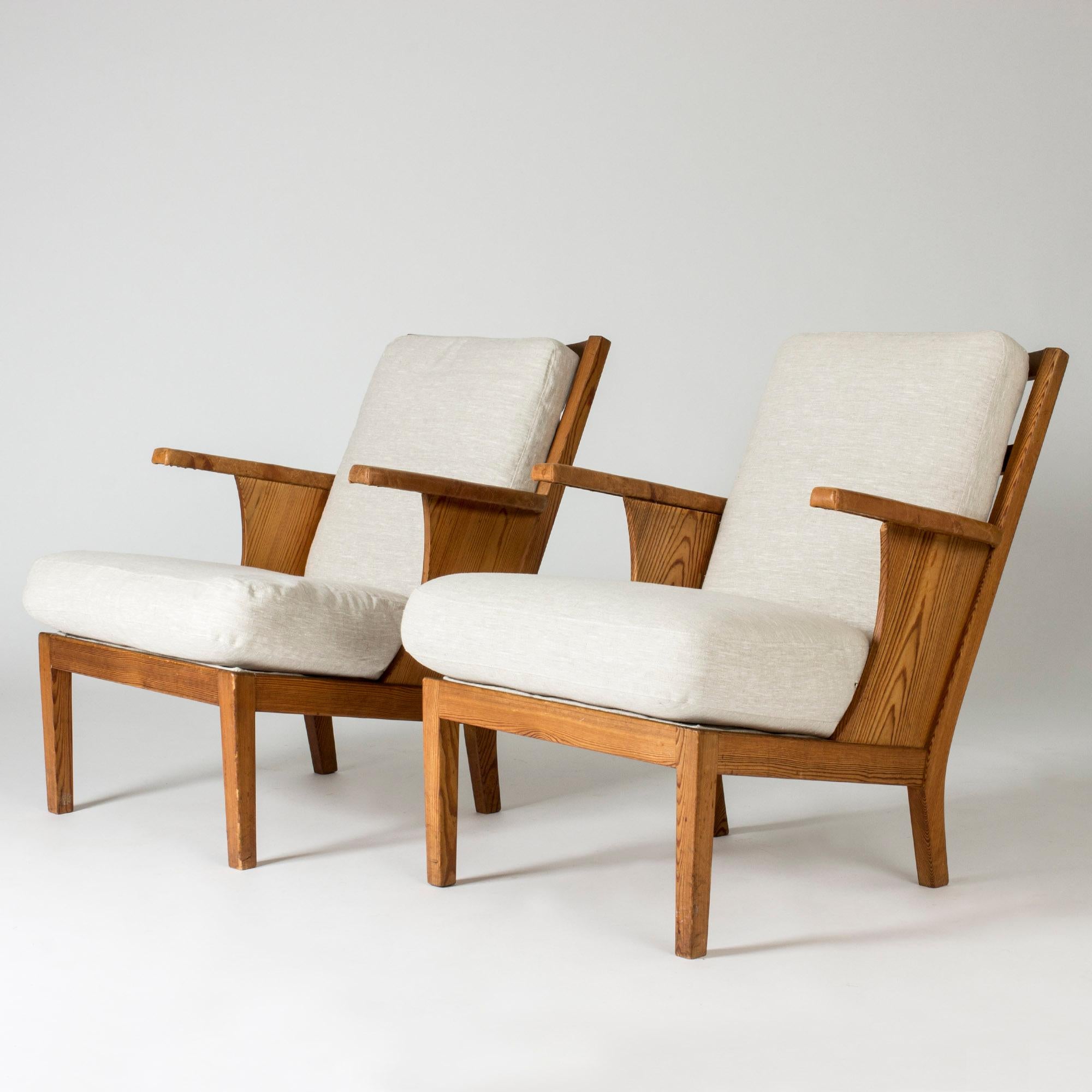 Pair of functionalist lounge chairs by Carl Malmsten, made from pine with leather armrests and linen upholstery. Beautiful woodgrain, timeless design.